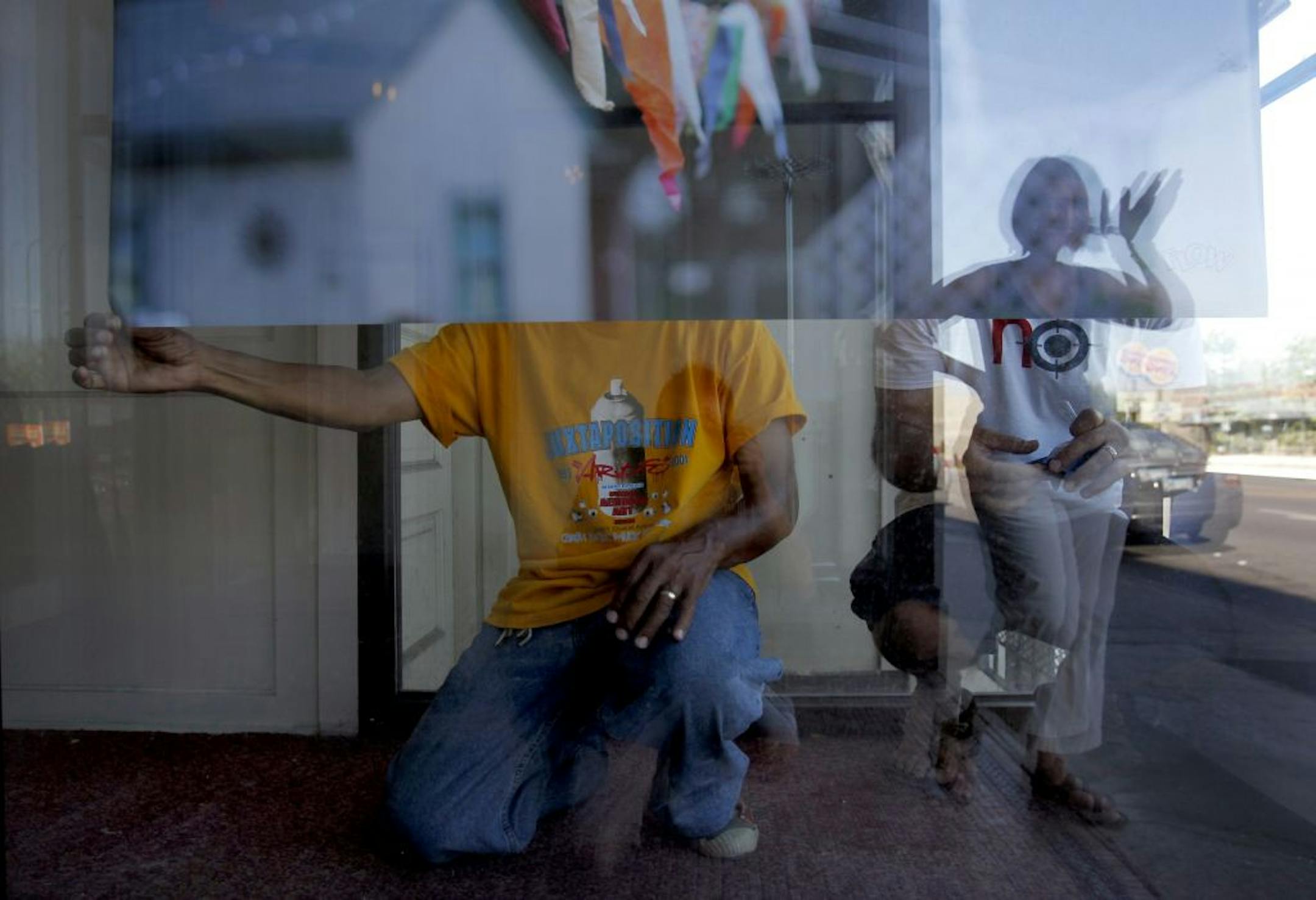 Bill Cottman and Ariah Fine got a wave from Dudley Voigt as they installed a print in a window at Neighborhoods Organizing for Change on Broadway Ave. in North Minneapolis on Monday.