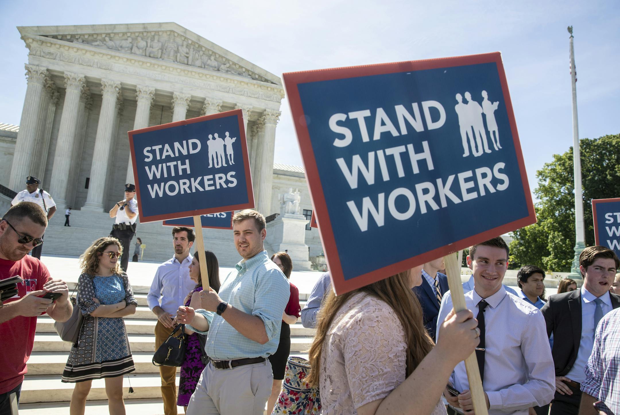 FILE - In this Monday, June 25, 2018 file photo, people gather at the Supreme Court awaiting a decision in an Illinois union dues case, Janus vs. AFSCME, in Washington. An Oregon state employee and a labor union have reached a settlement over her lawsuit seeking payback of obligatory union fees, marking the first refund of forced fees since the U.S. Supreme Court ruled in late June that government workers can't be required to contribute to labor groups, the employee's lawyers said Monday, July 3