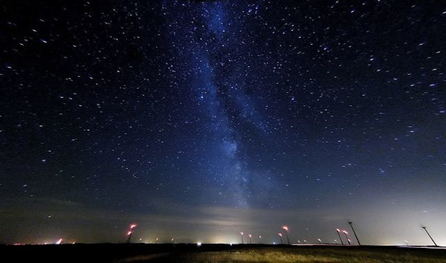 The Milky Way shown over the countryside near Hendricks, MN. Wind generators, with their red lights atop, turned in the wind along the crest of the Buffalo Ridge. "Light bombs" (or so called by star gazers when referring to light pollution from near by cities) can be seen from ( L. to R.) Tyler, Lake Benton, Pipestone (straight ahead), and Brookings, SD (right).