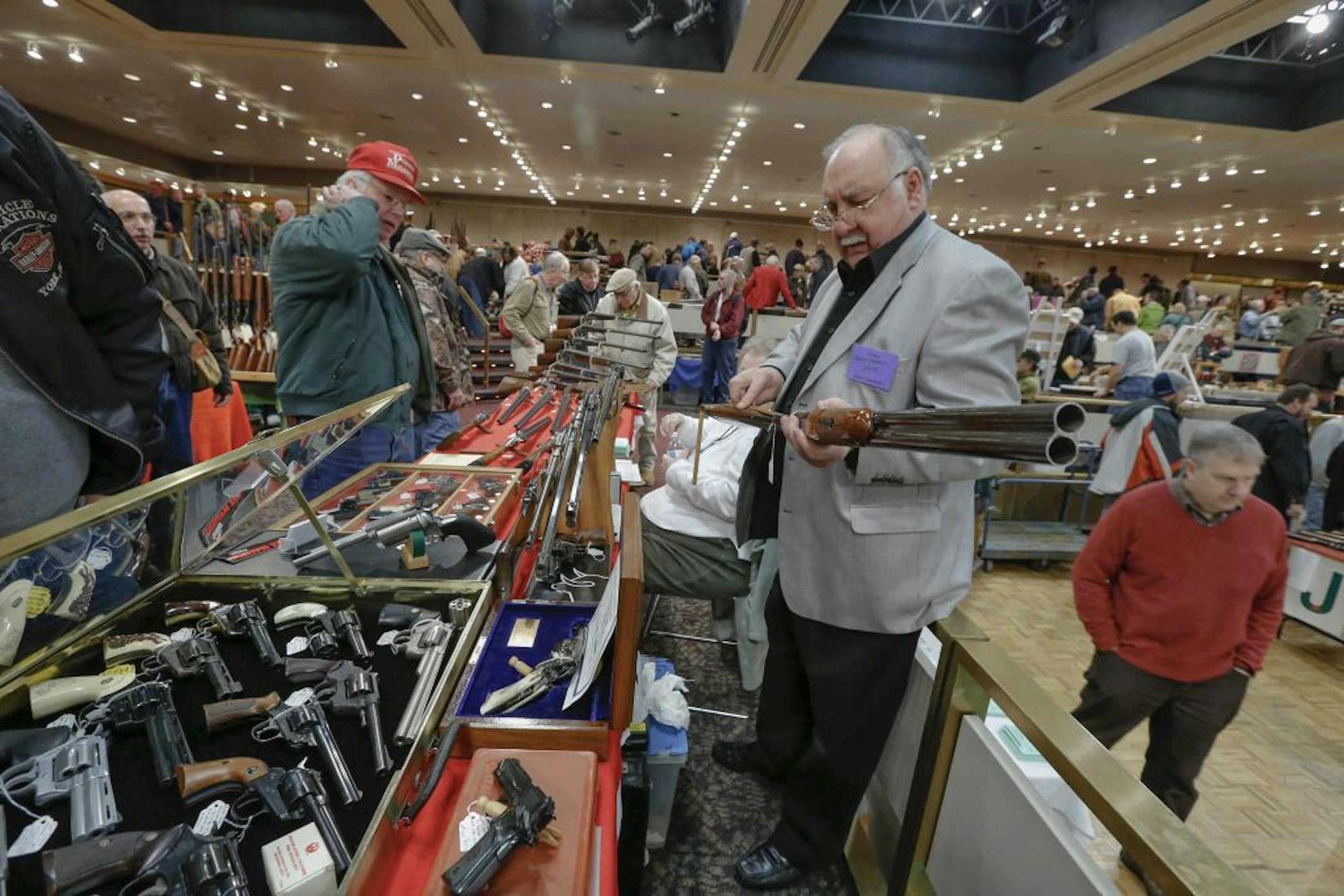 David Petronis of Mechanicville, NY, who owns a gun store, holds a shotgun at his table during the annual New York State Arms Collectors Association Albany Gun Show at the Empire State Plaza Convention Center, on Saturday, Jan. 26, 2013, in Albany, N.Y.