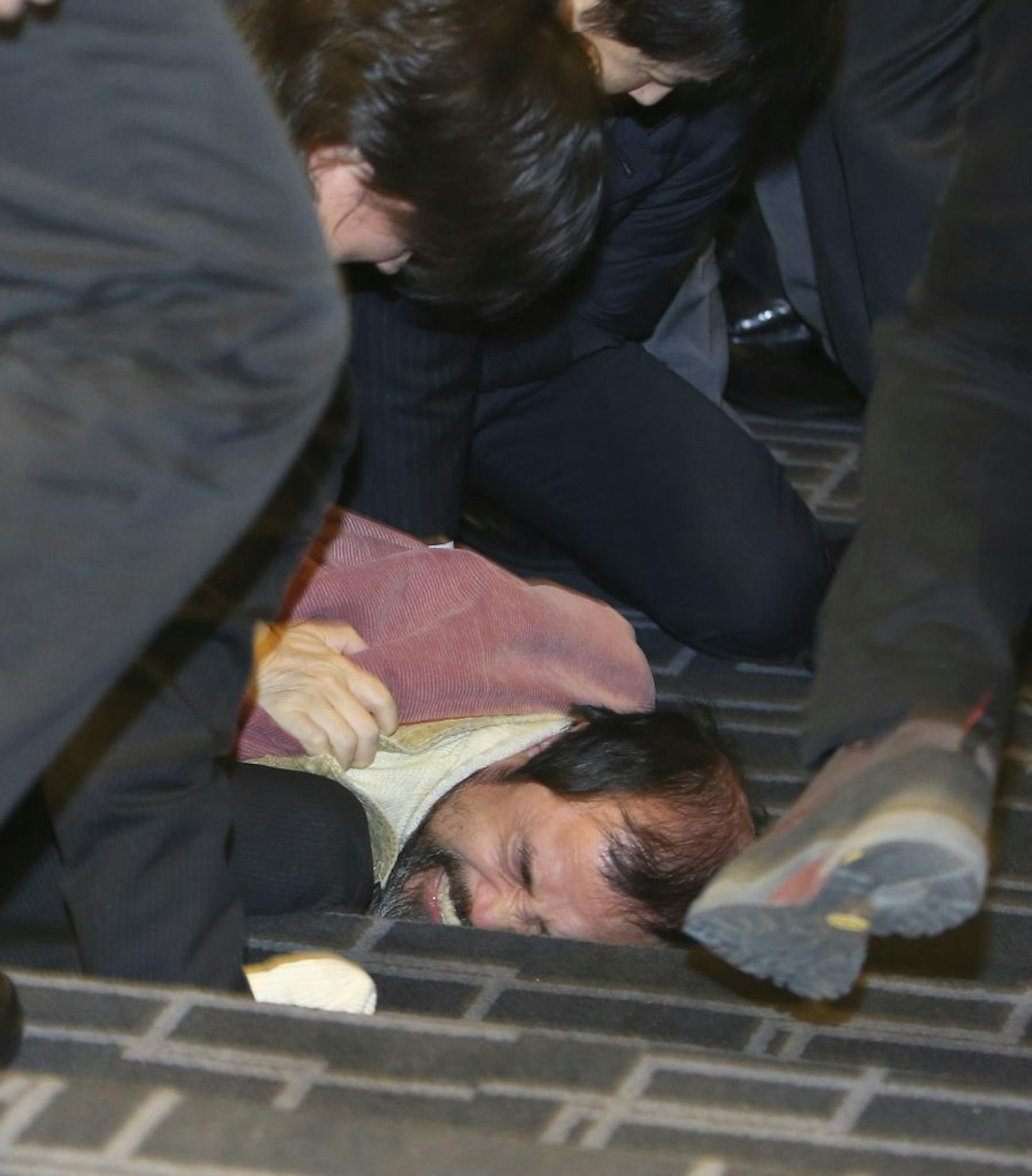 A suspect, bottom, identified by police as a 55-year-old, surnamed Kim, is overwhelmed by participants at a lecture hall in Seoul, South Korea, Thursday, March 5, 2015. U.S. Ambassador Mark Lippert was slashed on the face and wrist by a man wielding a blade and screaming that the rival Koreas should be unified, South Korean police said Thursday. (AP Photo/Yonhap, Kim Ju-Sung) KOREA OUT