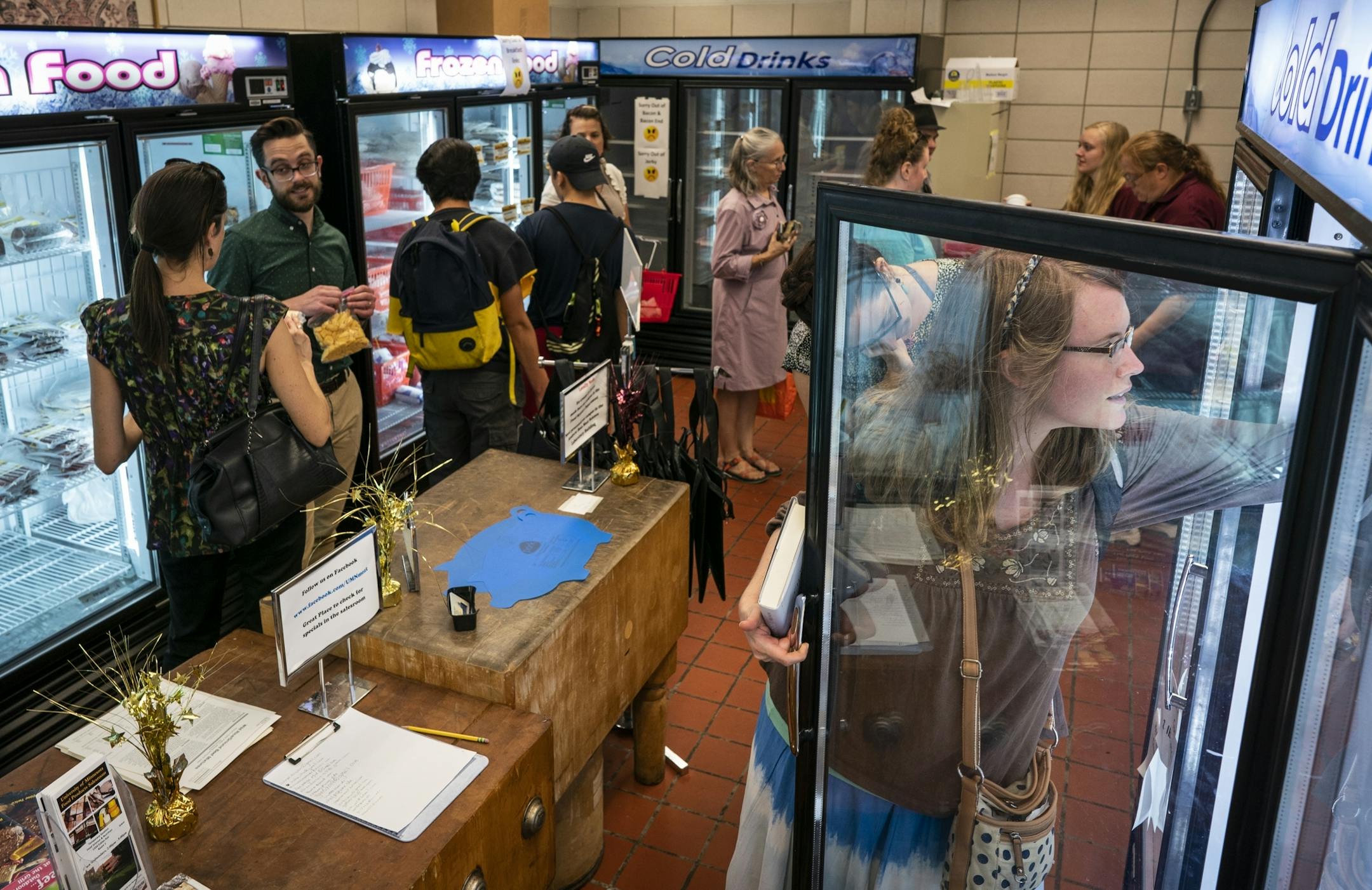 U graduate student Jenn Carnell, right, selects some cheese from the case during a busy afternoon at the Meat and Dairy salesroom.