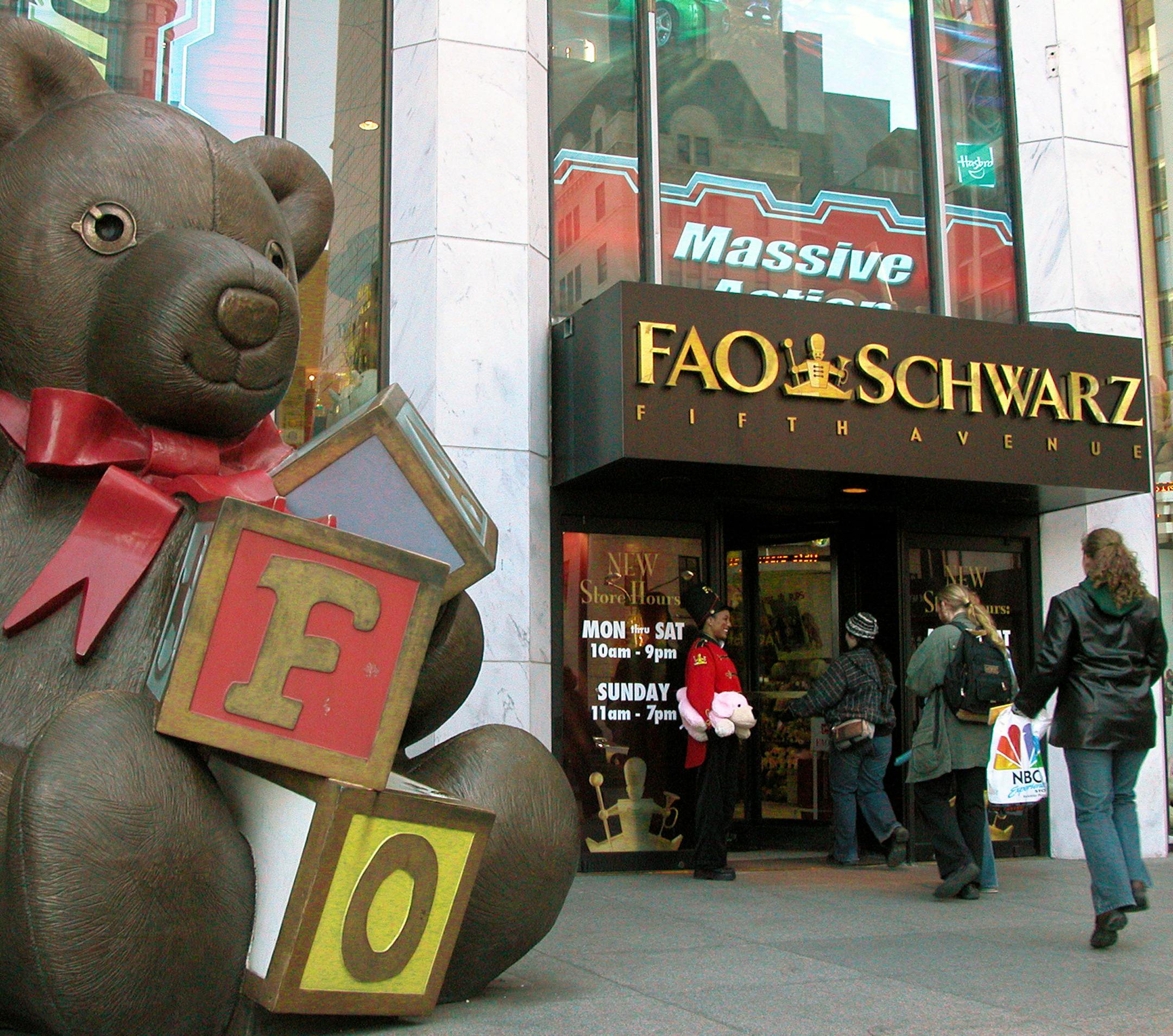 FILE - In this Nov. 10, 2003 file photo, customers pass a statue of a teddy bear and a doorman dressed as a toy soldier as they enter the FAO Schwarz on Fifth Avenue in New York. The store is closing its doors for good on Wednesday, July 15, 2015, though it may reopen elsewhere in midtown Manhattan. Owner Toys R Us announced the decision in May, citing costs. (AP Photo/Rich Kareckas, File)