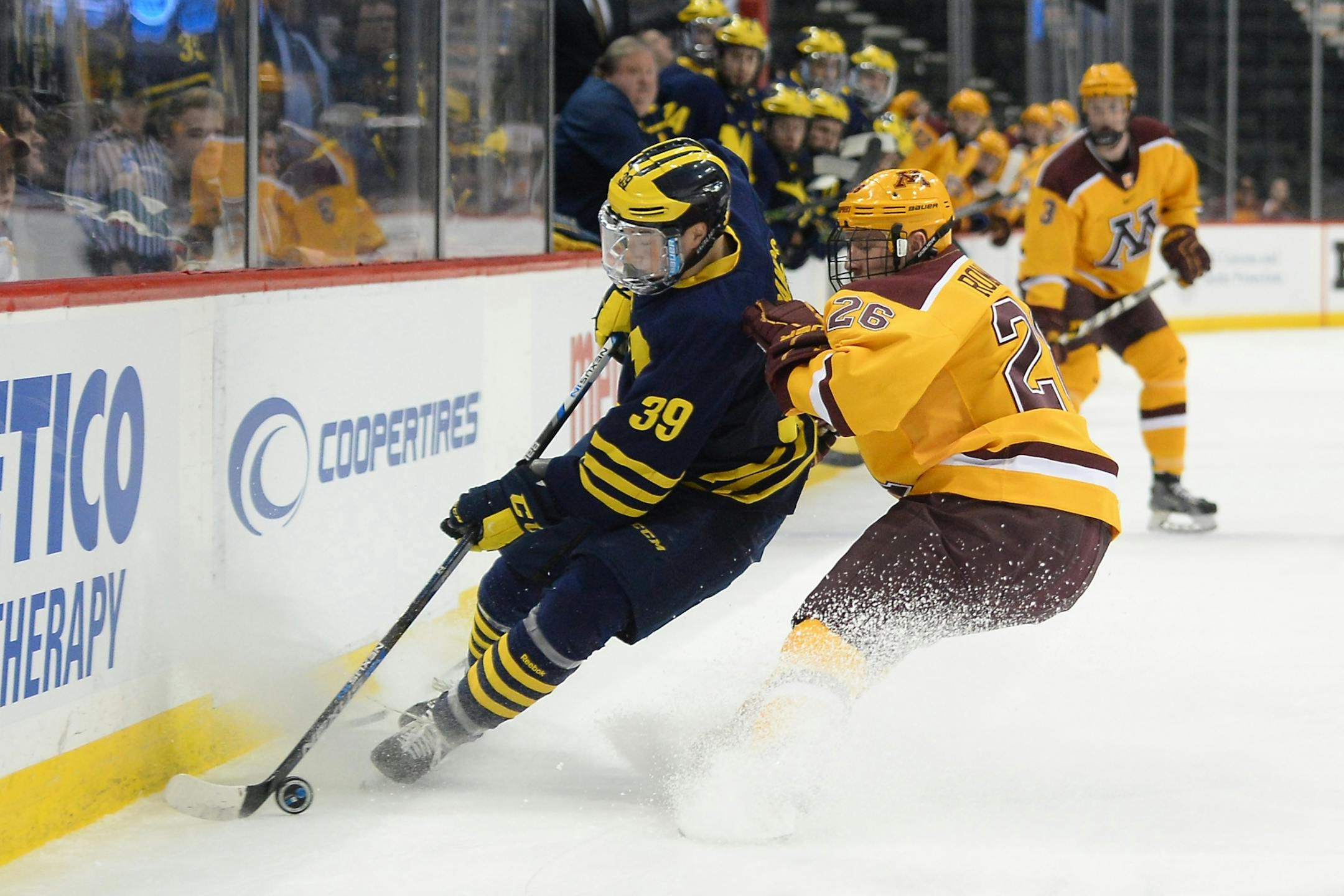 Minnesota Golden Gophers center Darian Romanko (26) challenged by Michigan Wolverines forward Dexter Dancs (39) for the puck at the boards in Michigan's zone during the first period Saturday.