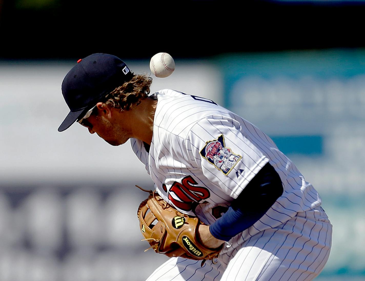 Minnesota Twins shortstop Brian Dozier loses the ball on a fielding error as Pittsburgh Pirates' Jeff Larish reaches first first base in the ninth inning of a spring training exhibition baseball game, Sunday March 10, 2013, in Fort Myers, Fla. (AP Photo/David Goldman)