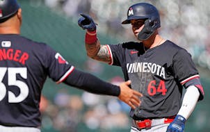 Minnesota Twins' Jose Miranda, right, points to teammates after hitting a one-run single during the seventh inning of a baseball game against the Chic