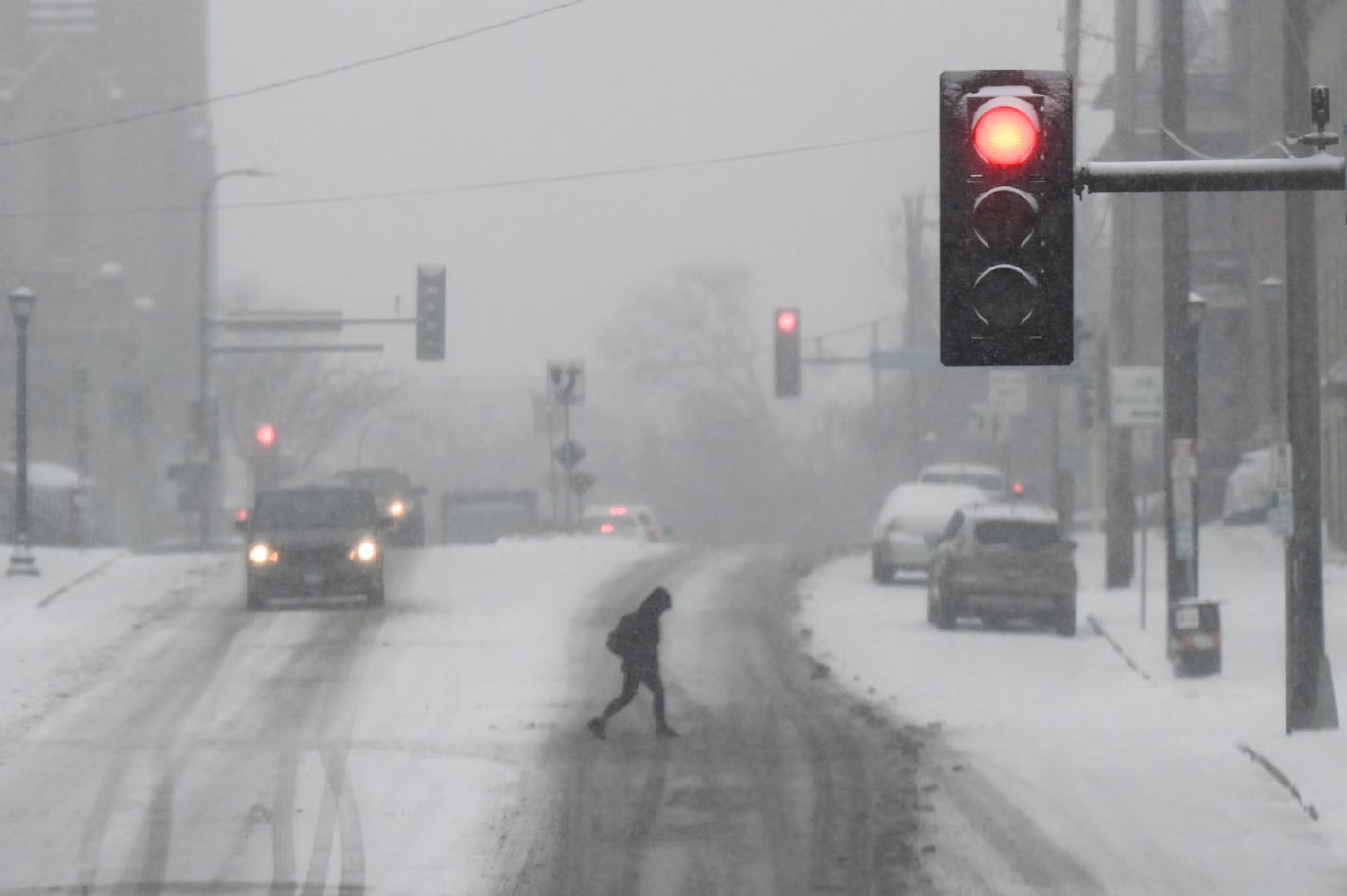 A pedestrian crosses the street on West Franklin Avenue near Lyndale Friday, Dec. 10, 2021 in Minneapolis, Minn. The Twin Cities saw the first significant snowfall of the season Friday, with up to a foot of snow possible overnight into Saturday for some areas. ] AARON LAVINSKY • aaron.lavinsky@startribune.com