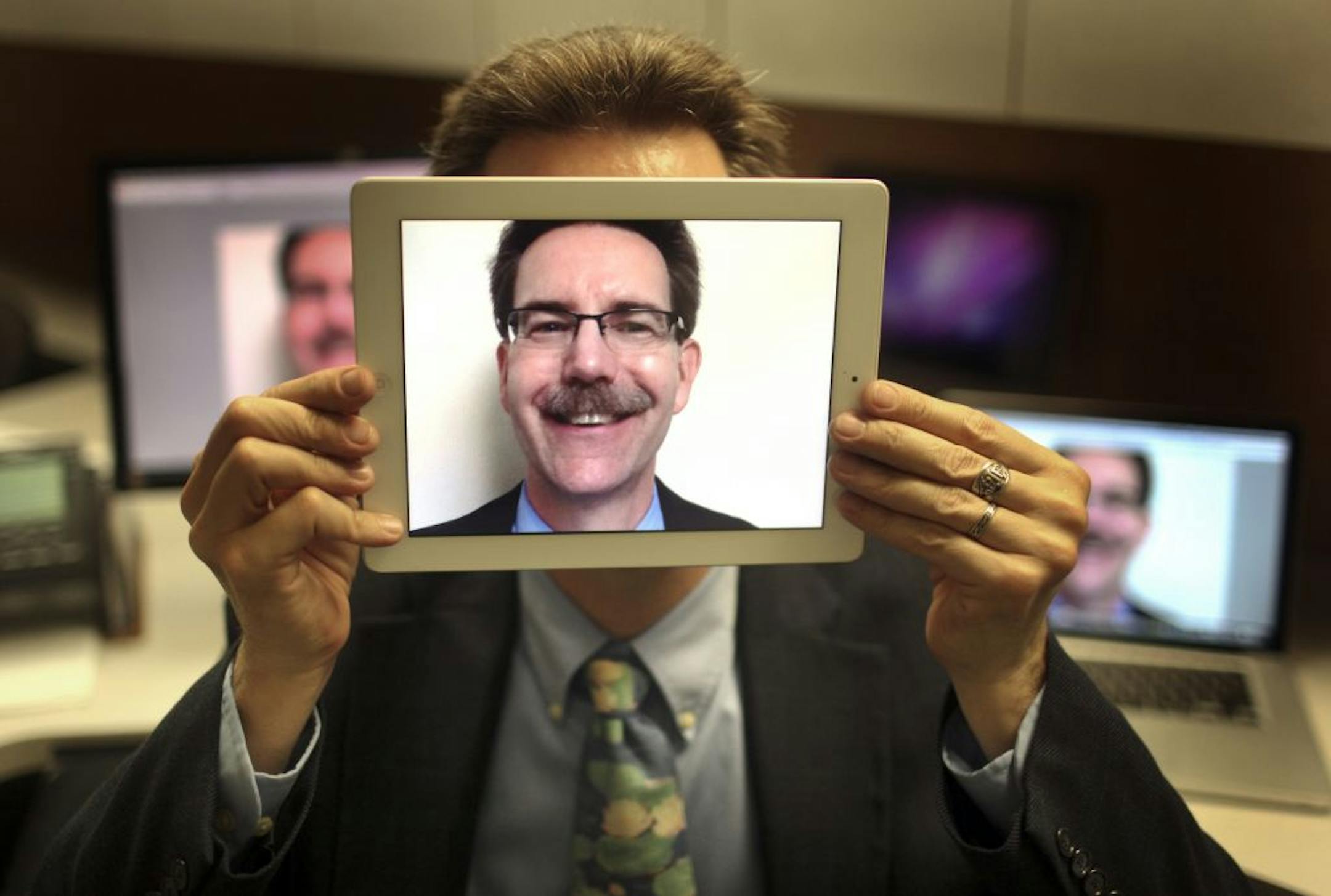 Patrick Plant, holding a portrait shot on his iPad in his office, will soon retire from his position as tech guru for the Anoka-Hennepin School District.