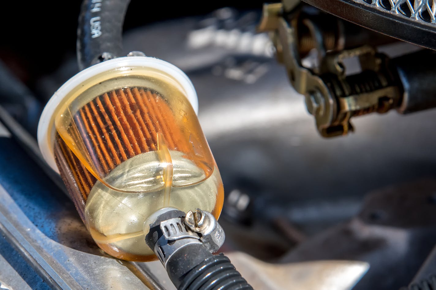 A fuel filter in a car. Gasoline can be seen in the filter. Closeup view.