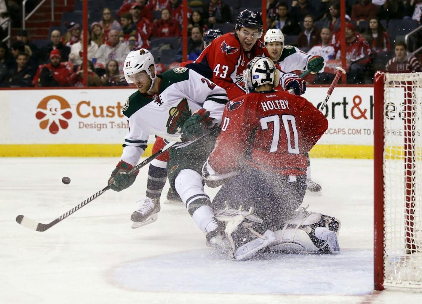 Minnesota Wild center Kyle Brodziak (21) can't get the puck that was deflected by Washington Capitals goalie Braden Holtby (70), with right wing Tom Wilson (43) nearby, during the second period of an NHL hockey game Thursday, March 5, 2015, in Washington.