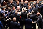5-Star Movement lawmaker Leonardo Donno, center top, is protected by parliament employees from other lawmakers during brawl in the lower chamber of de