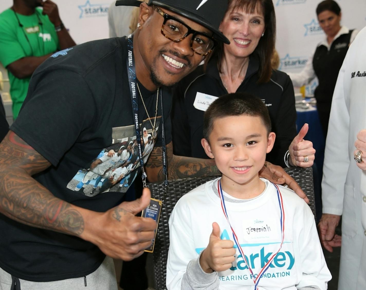 Ted Ginn Jr. of the Carolina Panthers celebrated as Jeremiah received a free hearing aid at a pre-Super Bowl bash in California sponsored by the Starkey Hearing Foundation.