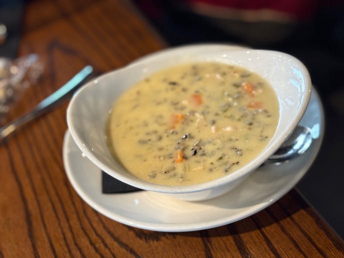 A bowl of creamy chicken wild rice soup at Grackle.