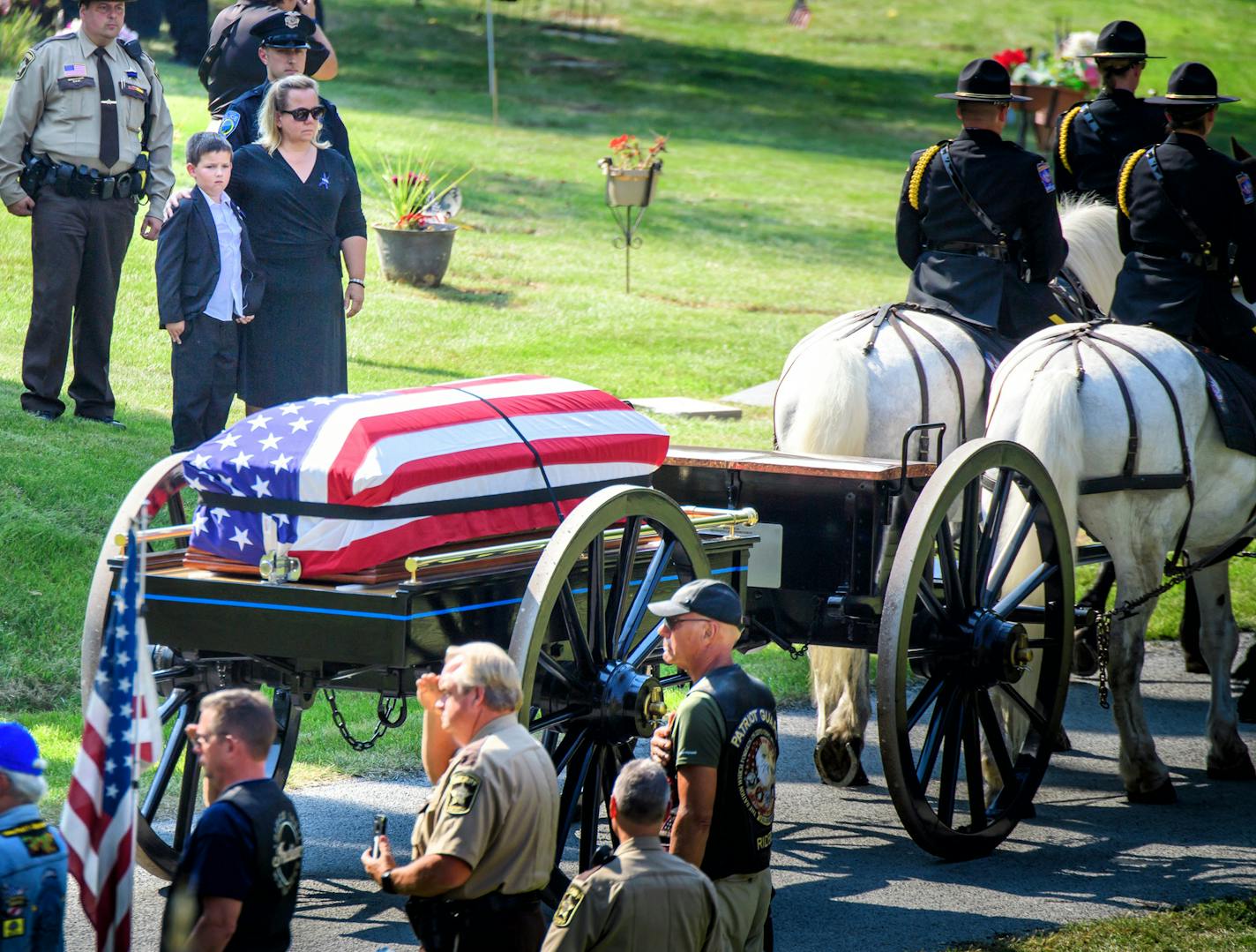 Shawn Mathews, widow of Wayzata officer William Mathews, stood with their 7-year-old son, Wyatt, as a horse-drawn caisson carried her husband's casket in Summit Park Cemetery on Thursday.