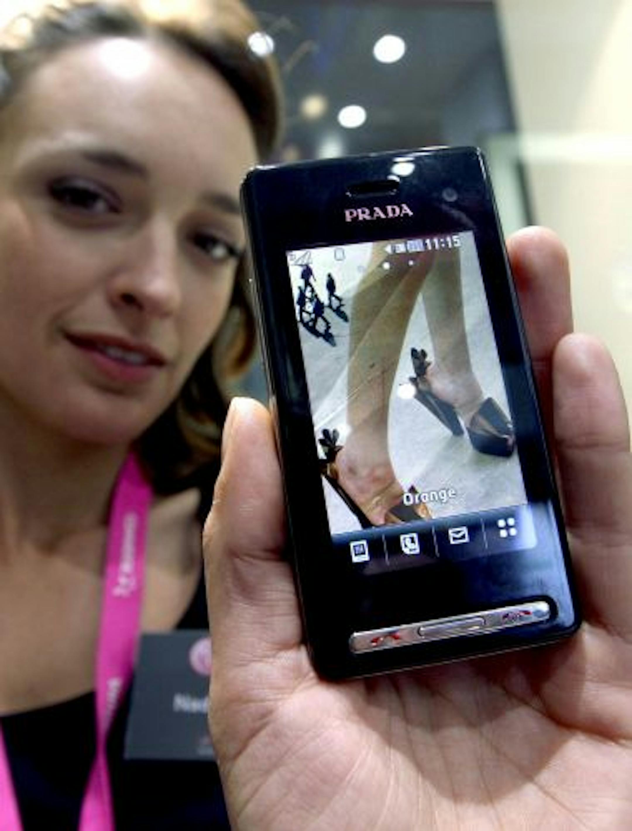 epa01637738 A conference hostess displays the new LG KF900 Prada mobile phone during the first day of the GSMA World Mobile Congress held in Barcelona, Spain, on 16 February 2009. The World Mobile Congress trade show is the venue for 1.300 exhibitors. According to the organizers, the GSMA Mobile World Congress (formerly 3GSM World Congress) combines the world's largest exhibition for the mobile industry with a congress that brings together prominent leaders and personalities from mobile operator