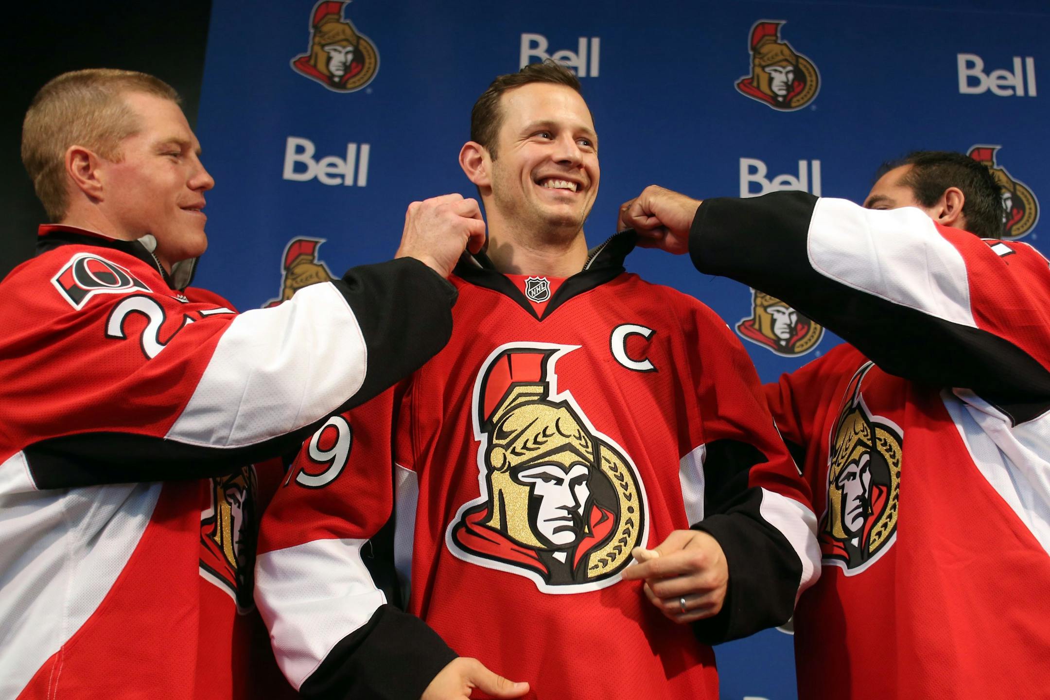 Ottawa Senators' Jason Spezza, center, has his captain's team jersey adjusted by assistant captains Chris Neil, left, and Chris Phillips after he was named the team's captain on Sept. 13. The Senators are Michael Russo's pick to hoist the Stanley Cup this season.