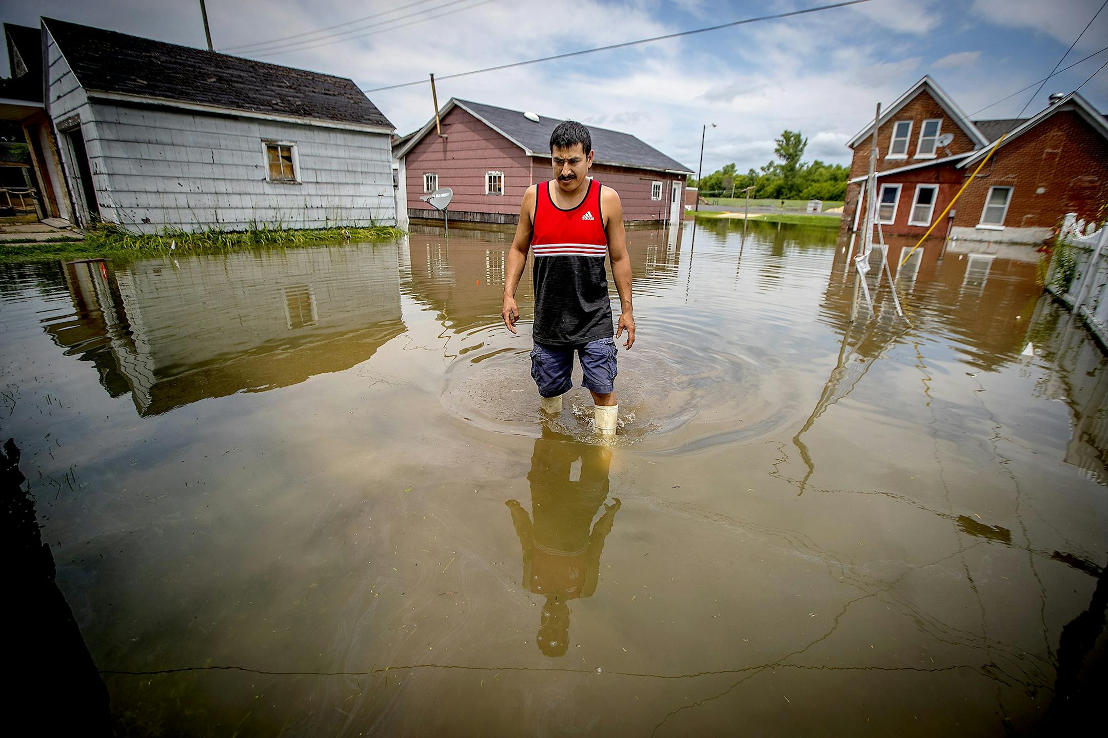Miguel Aguirre, who is employed at the local Ashley Furniture, made his way assessing the damage to his back yard, Thursday, July 20, 2017 in Arcadia, Wis. Much of the town was flooded after Wednesday night's rain flooding the Trempealeau River and Turton Creek.