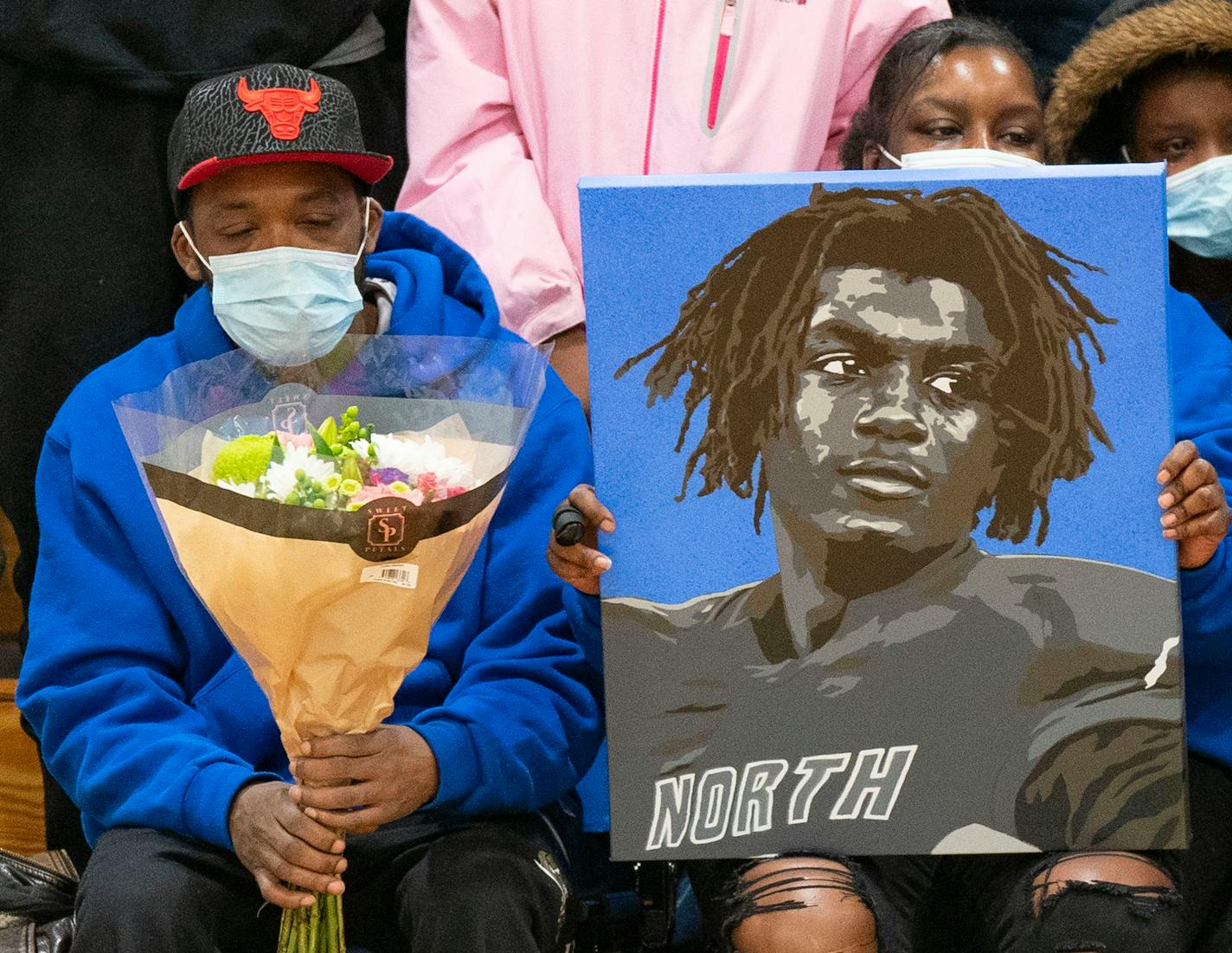 Deshaun Hill Sr. and Tuesday Sheppard, Deshaun Hill Jr.'s parents, hold a portrait of Hill Jr. after it was presented to them during halftime of the North Community High School boy's basketball team's game against Hopkins Saturday, Feb. 12, 2022 at North Community High School in Minneapolis, Minn. The 15-year-old sophomore died on Thursday, Feb. 10, 2022, a day after he was found with a gunshot wound near the intersection of Golden Valley Road and Penn Avenue N. ]