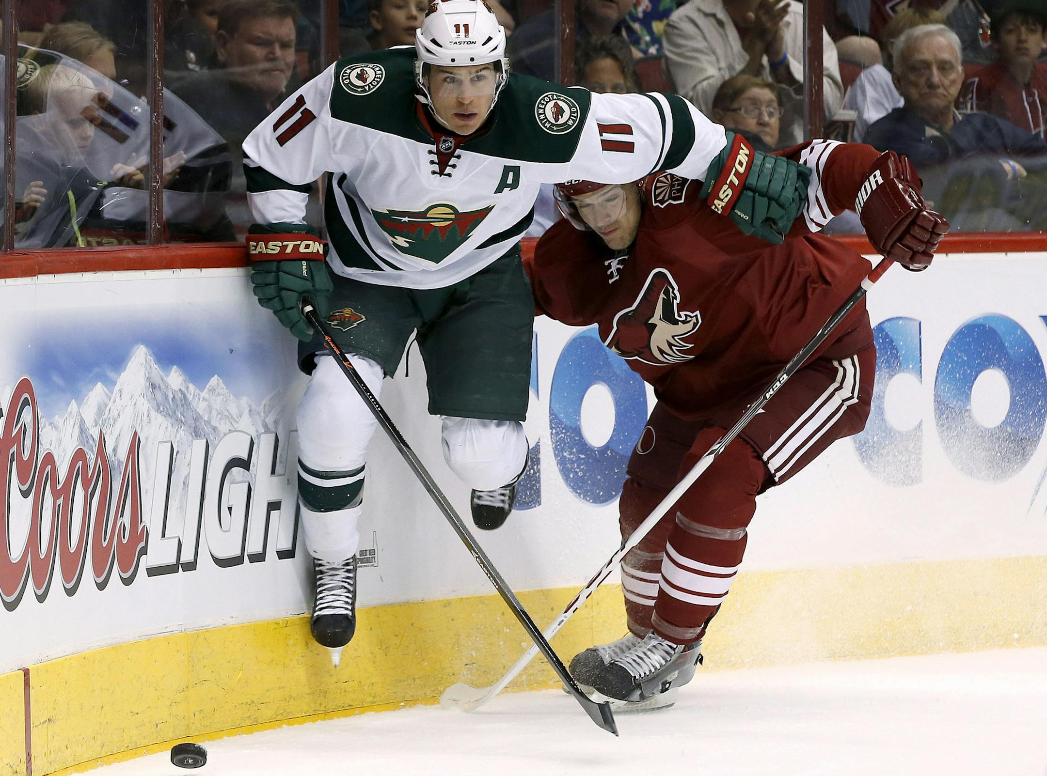 Minnesota Wild's Zach Parise (11) and Phoenix Coyotes' Zbynek Michalek, of the Czech Republic, collide behind the goal during the first period of an NHL hockey game, Saturday, March 29, 2014, in Glendale, Ariz. (AP Photo/Ross D. Franklin)