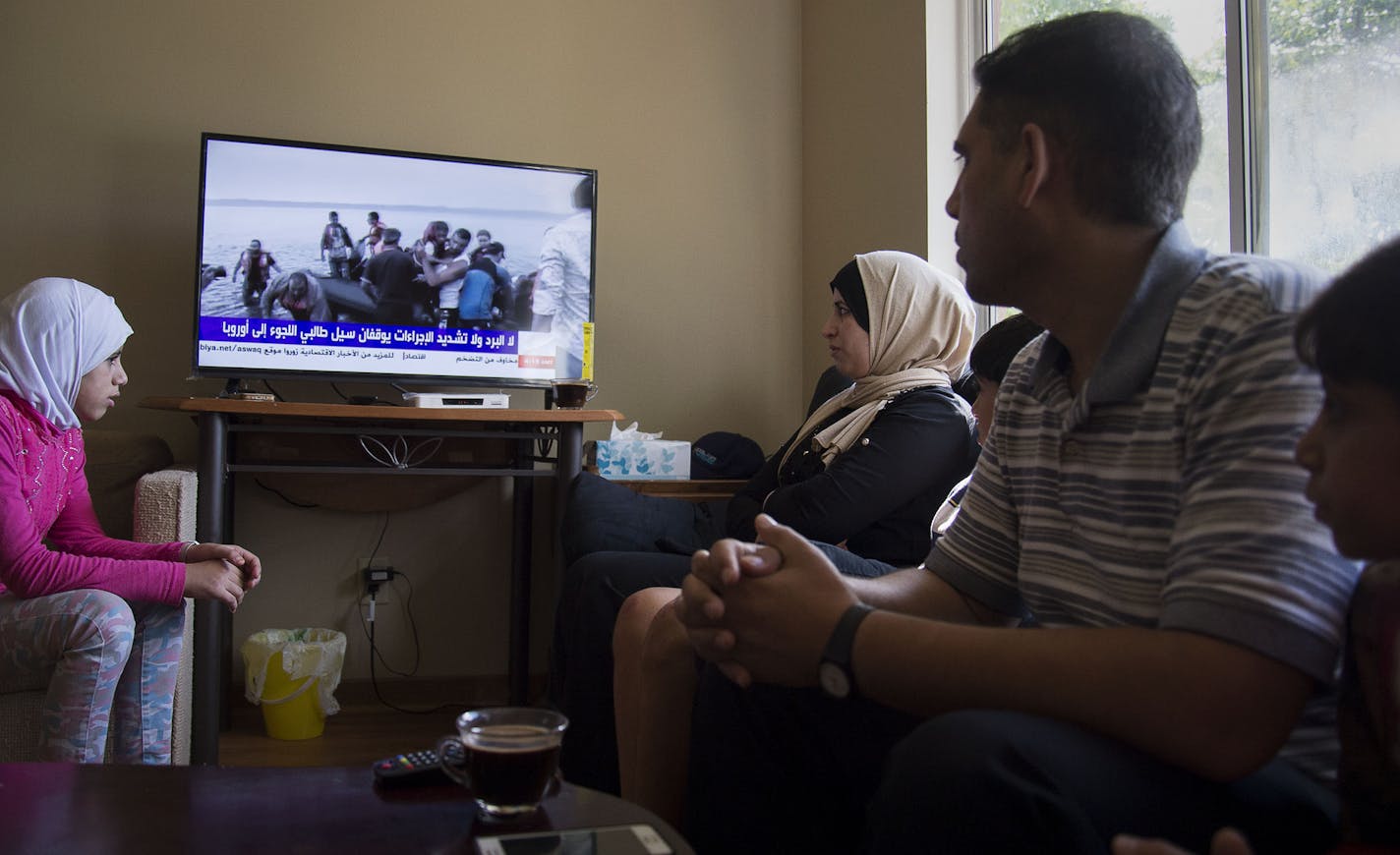 From left, Noura Mohamad Khir Alobeid, 14, watched the news with her parents, Ramia Abdulkarim Aljasem and Mohamad Khir A Al Obeid, along with her siblings at their home in Rochester, Minn., on Friday September 11, 2015. ] RACHEL WOOLF The family of seven are refugees from Syria that came to Rochester, Minn. in April.