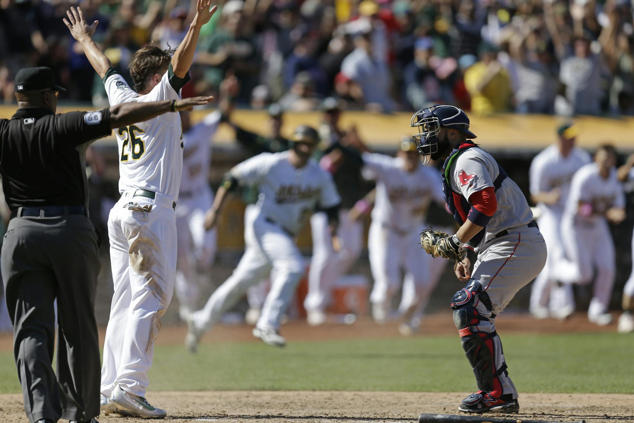 Oakland Athletics' Danny Valencia (26) celebrates after scoring the winning run behind Boston Red Sox catcher Sandy Leon, right, in the ninth inning of a baseball game Sunday, Sept. 4, 2016, in Oakland, Calif. (AP Photo/Ben Margot)