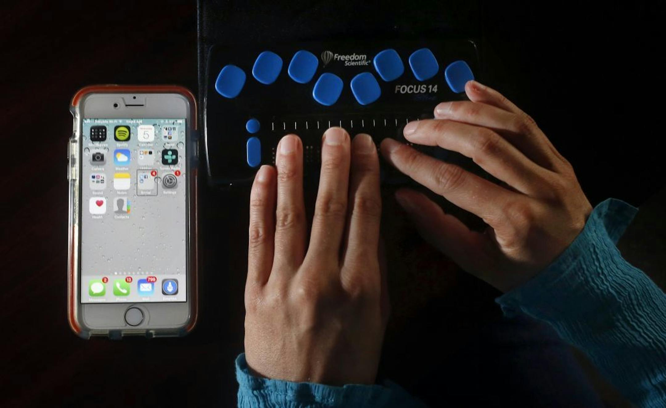 Erin Lauridsen, an assistive technology educator for the Independent Living Resource Center, and blind since birth, uses a cellphone that is bluetooth connected to a refreshable braille display at her office in San Francisco on August 5, 2015.