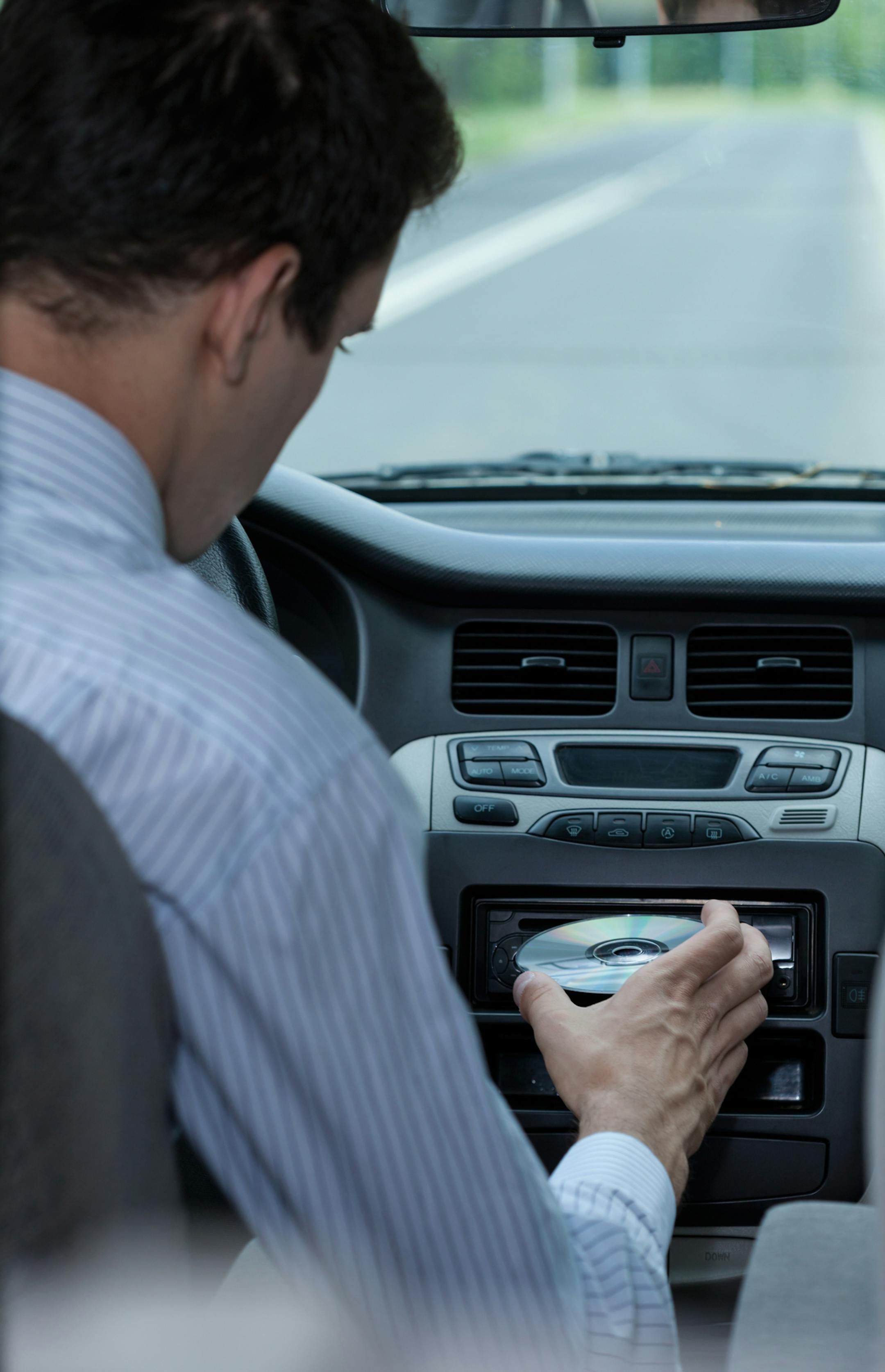 A driver inserting a CD in the car