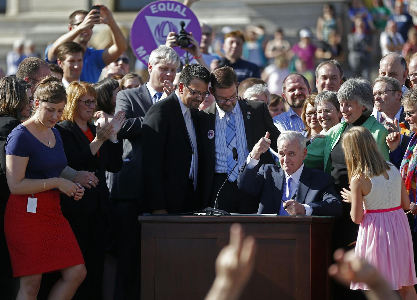 Minnesota Gov. Mark Dayton signs the gay marriage bill into law in front of the State Capitol in St. Paul, Minn., Tuesday, May 14, 2013 The bill signing ended an intense two years for gay marriage supporters and opponents in the Midwestern state, which swung from a failed push to constitutionally ban same-sex weddings into a successful bid to becoming the 12th state to affirm them. (AP Photo/The Star Tribune, Richard Tsong-Taatarii) ORG XMIT: MIN2013061415093806