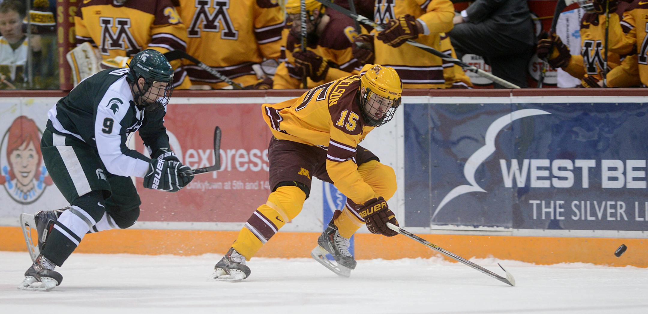 Gophers forward A.J. Michaelson chases the puck with Michigan State forward Connor Wood right behind him.