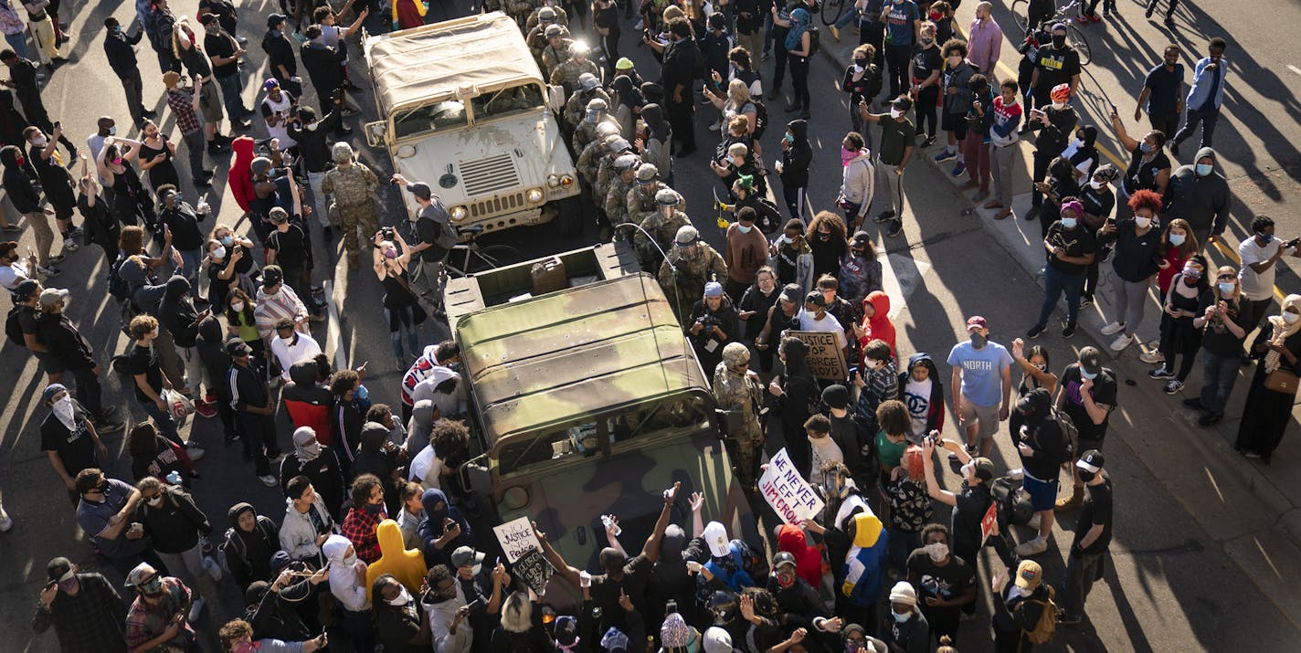 A group of protesters surrounded several National Guard vehicles that were driving on Lake Street towards the blockade under the Hiawatha Light Rail station and forced them to reverse out in Minneapolis, Minn., on Friday, May 29, 2020. A peaceful protests turned increasingly violent in the aftermath the death of George Floyd during an arrest. Mayor Jacob Frey ordered a citywide curfew at 8 p.m. local time, beginning on Friday. (Renee Jones Schneider/Star Tribune via AP)