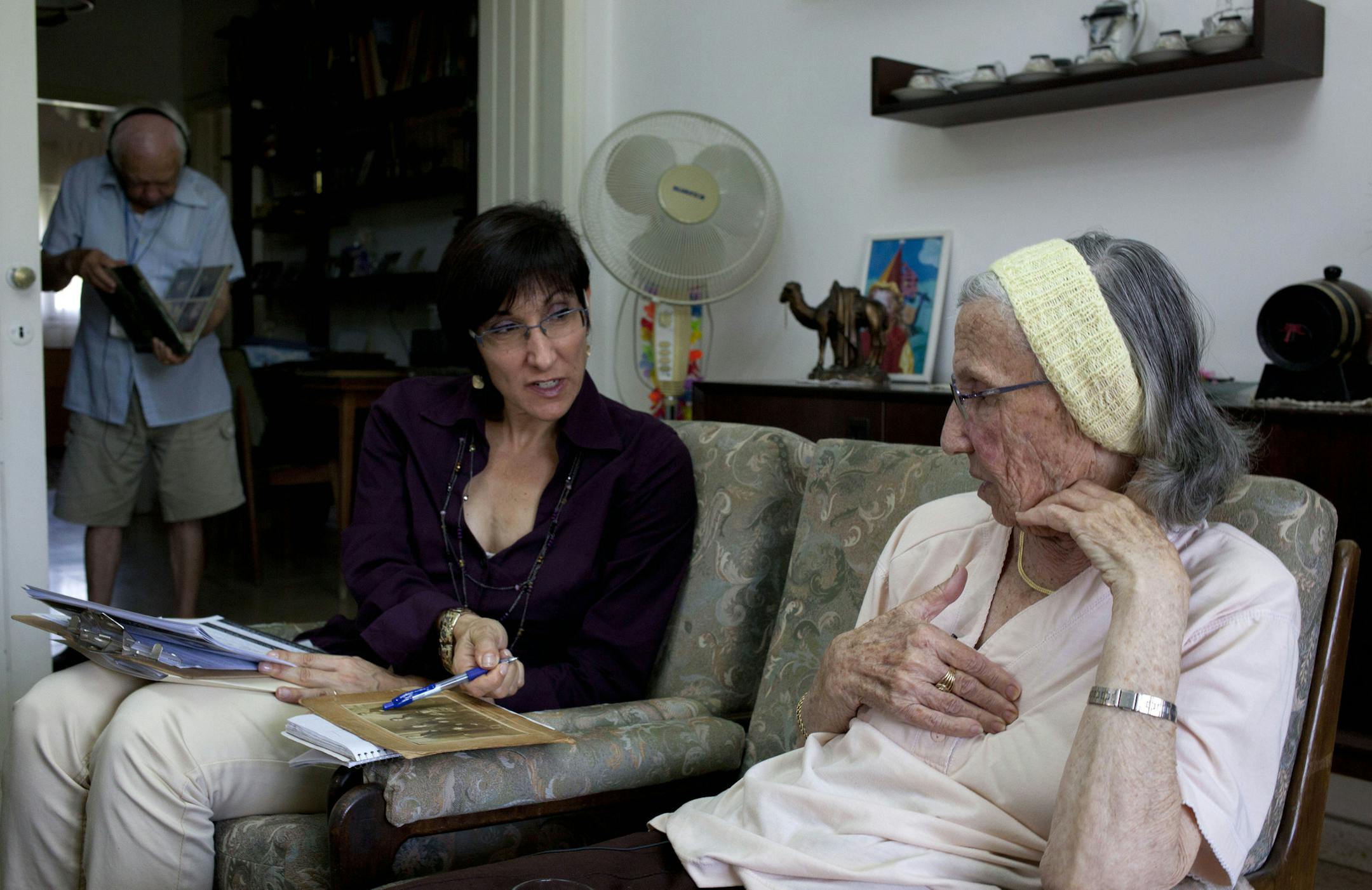 In this photo take on Sunday, May 5, 2013, Holocaust survivor Rivka Fringeru, 82, right, hold her chest as she speaks to Cynthia Wroclawski, director of Yad Vashem names collection project as they sit at her living room in Rehovot, central Israel. With a hand on her chest and moistness building in her eyes, 82-year-old Rivka Fringeru battled back tears as she reeled off a list of names she has rarely voiced in the past 70 years. First her father, Moshe, then her mother, Hava, and finally her two