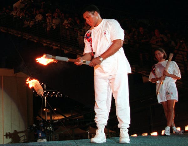 FILE - In this July 19, 1996, file photo, American swimmer Janet Evans looks on as Muhammad Ali lights the Olympic flame during the 1996 Summer Olympi