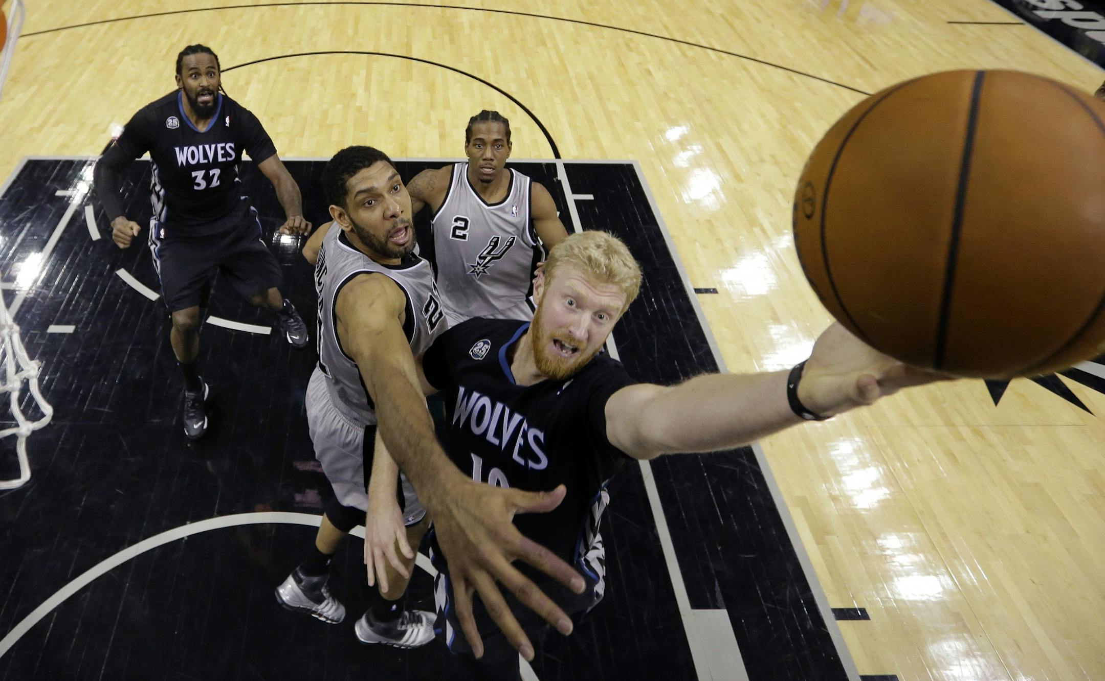 Minnesota Timberwolves' Chase Budinger, right, drives past San Antonio Spurs' Tim Duncan, center, to score during the first half of an NBA basketball game on Sunday, Jan. 12, 2014, in San Antonio.