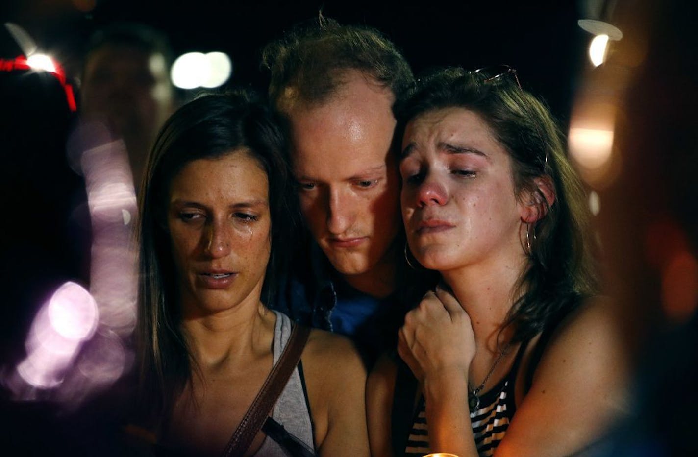 Mallory Cunningham, left, Santino Tomasetti, center, and Aubrey Reece attend a candlelight vigil in the parking lot of Ride the Ducks Friday, July 20, 2018, in Branson, Mo. One of the company's duck boats capsized Thursday night resulting in over a dozen deaths on Table Rock Lake.