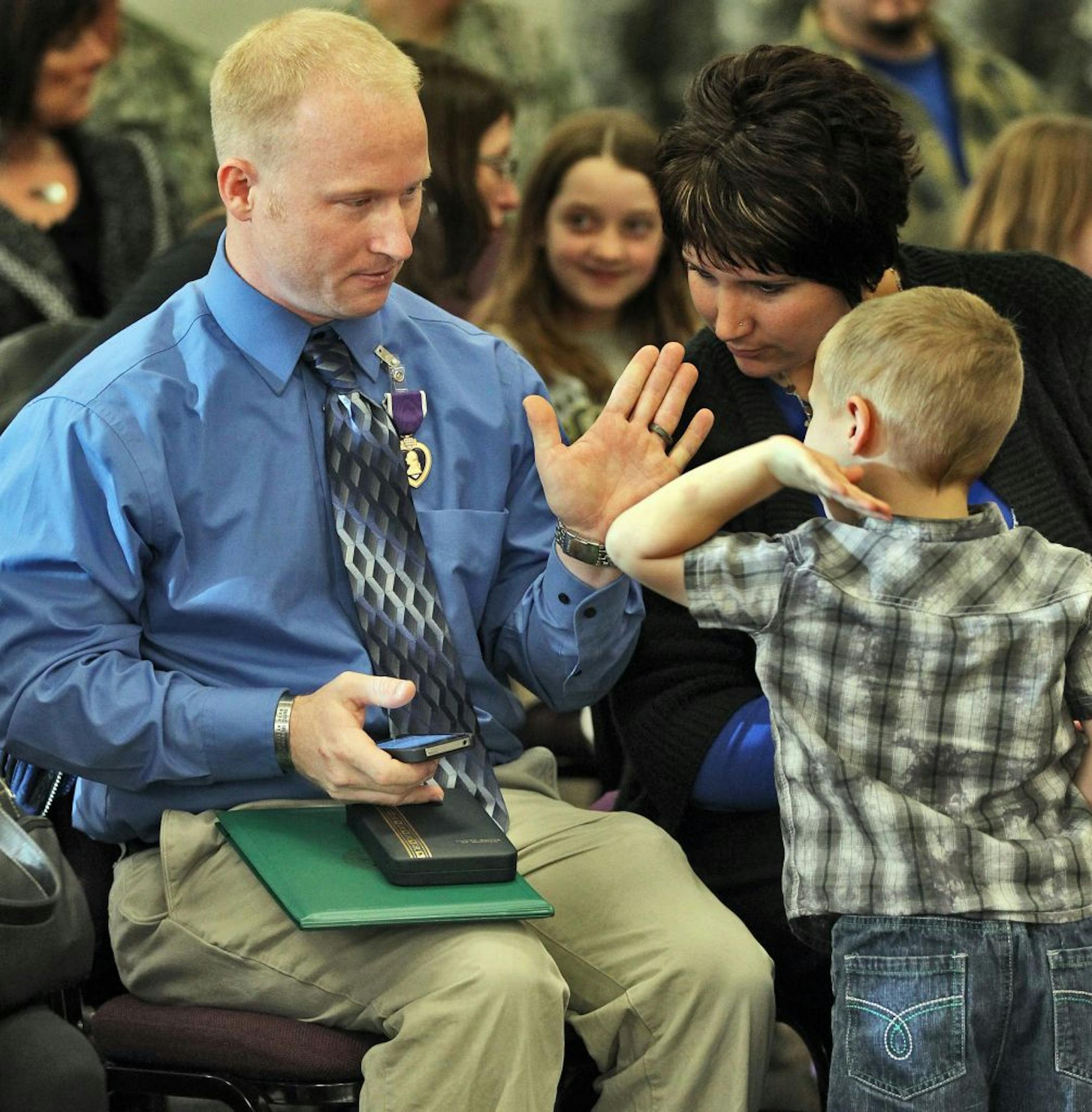 Sgt. Jesse Lund, a retired soldier from the Minnesota National Guard, was awarded a purple heart for his service in Iraq during ceremonies at Brooklyn Park Community Center. Lund's son Ethan Lund, 4, congratulated his dad with a high-five after Jesse Lund was awarded the purple heart.(MARLIN LEVISON/STARTRIBUNE(mlevison@startribune.com