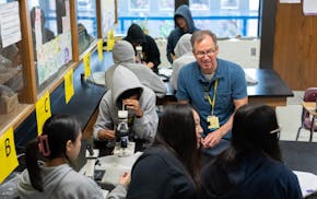 Tim Chase, a science teacher, works with eighth-graders to look at salt under a microscope during a physical science class at Murray Middle School in