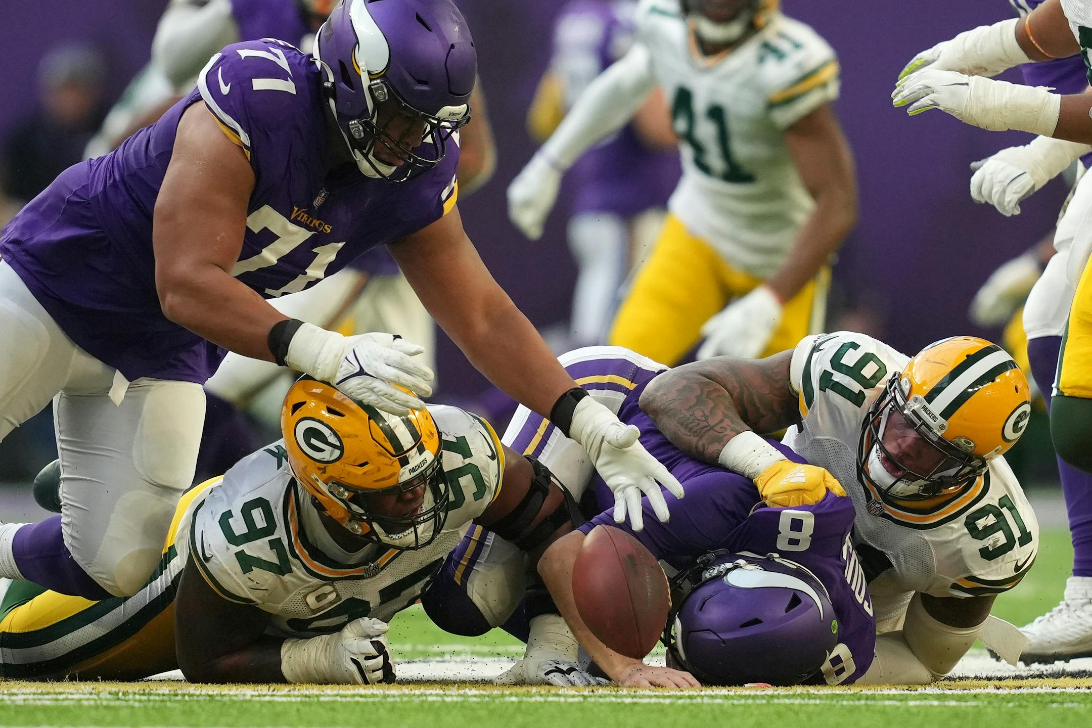 Minnesota Vikings offensive tackle Christian Darrisaw (71) looked to dive on the ball after Minnesota Vikings quarterback Kirk Cousins (8) fumbled it as he was sacked by Green Bay Packers outside linebacker Preston Smith (91) and nose tackle Kenny Clark (97) in the third quarter.