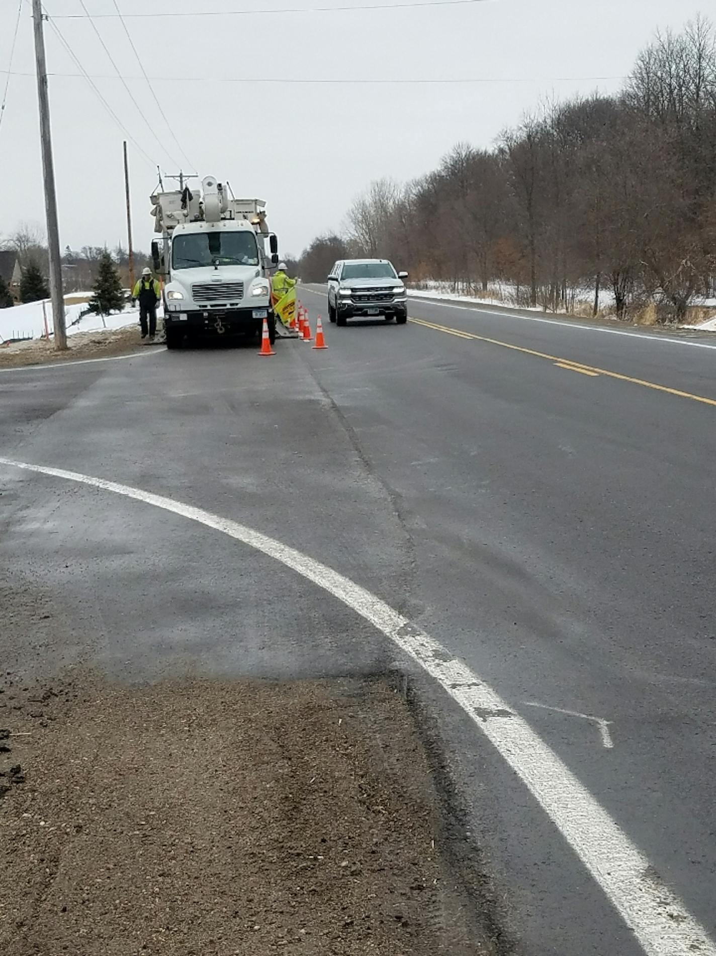 A motorists passes an Xcel Energy truck without moving over as utility crews moved power lines on County Road 30 in Mayer, Minn.