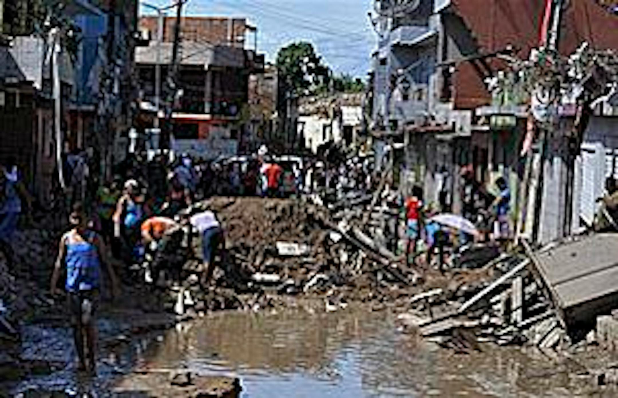 People work at getting debris cleared from a street after heavy rains in Barreiros, Pernambuco state, Brazil, Monday, June 21, 2010. Officials scrambled to get food and medical aid to two flood-hit Brazilian states where torrents of water ripped through towns, killing at least 41 people and driving 120,000 from their homes.(AP Photo/Alexandre Gondim-JC Imagem)