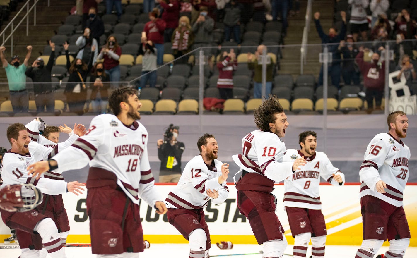 University of Massachusetts men's hockey players rush onto the ice to celebrate after defeating St. Cloud State 5-0 to claim the program's first national championship. ]