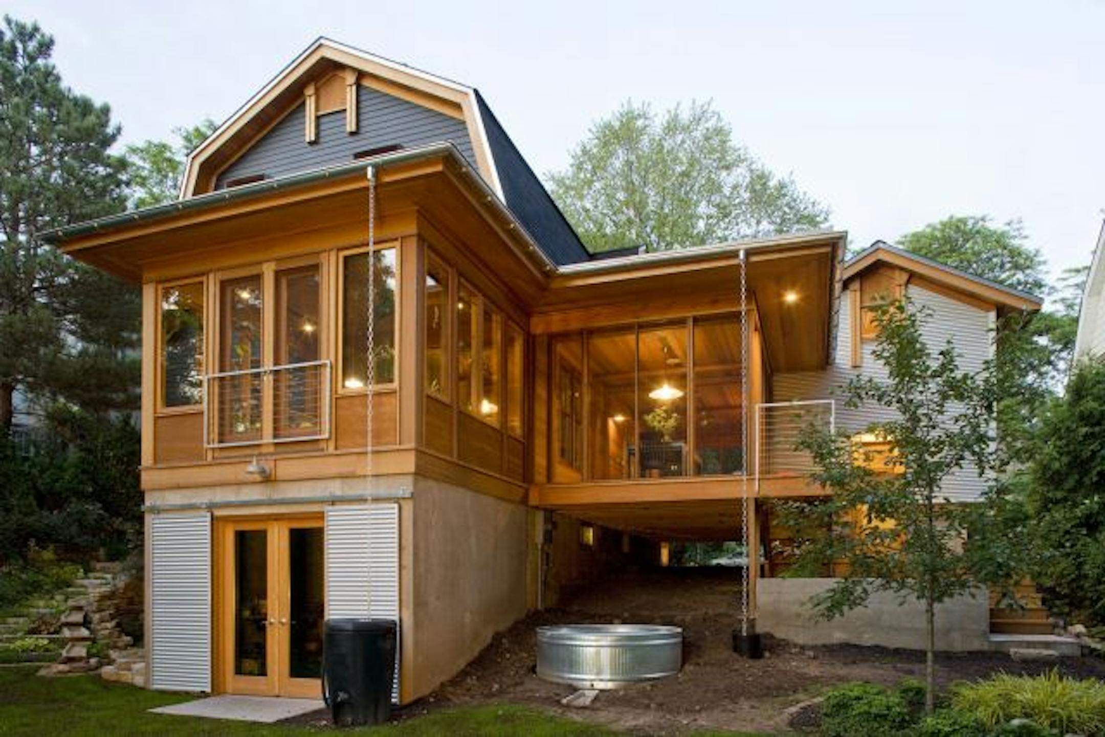 A back-yard view of SALA architect Eric Odor's renovated 1905 Dutch Colonial with a new screened porch floating between the orchid room and metal "granary," or garage.