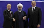 In this photo released by an official website of the office of the Iranian Presidency, Iranian President Hassan Rouhani, center, Russian President Vla