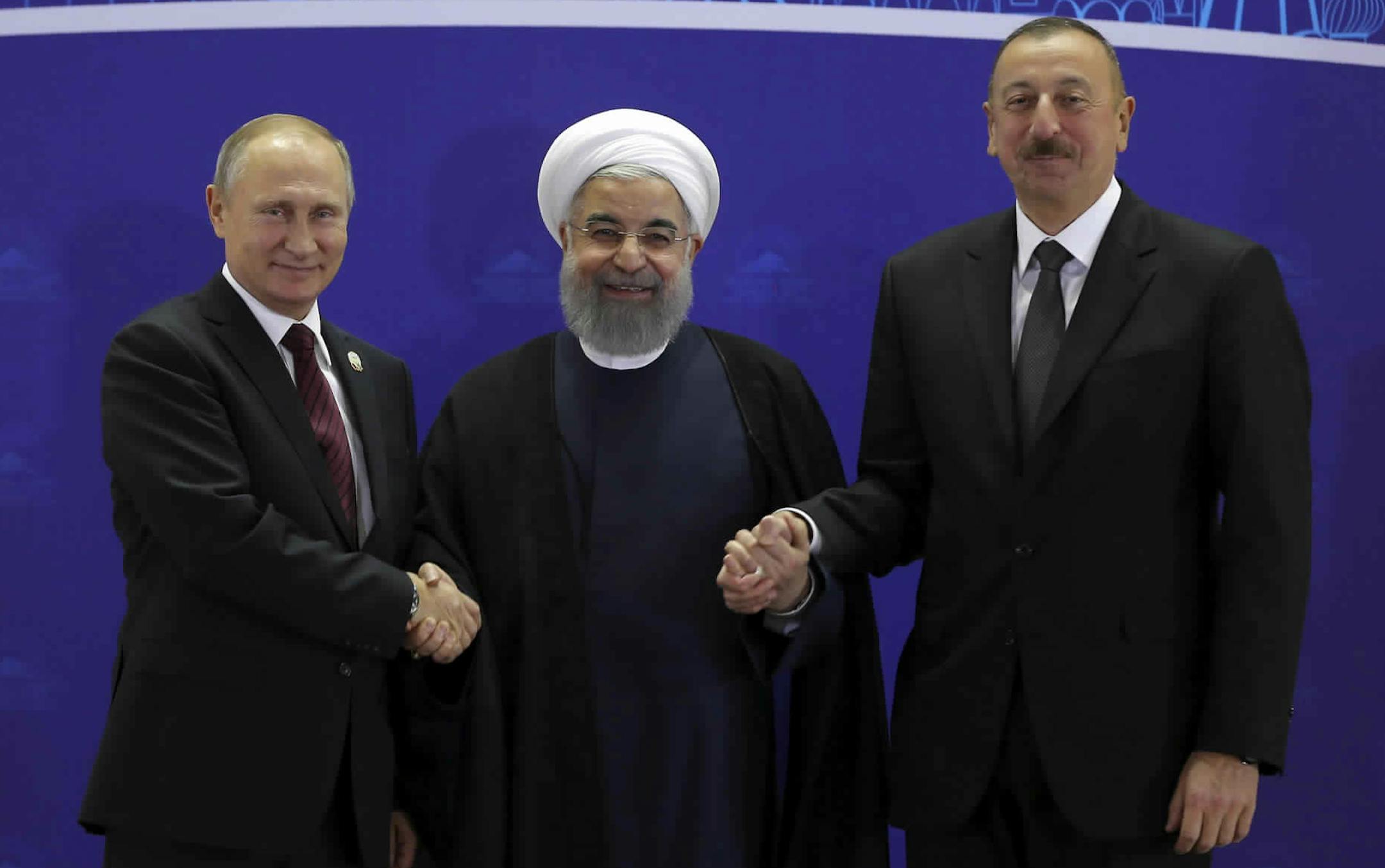 In this photo released by an official website of the office of the Iranian Presidency, Iranian President Hassan Rouhani, center, Russian President Vladimir Putin, left, and Azerbaijan's President Ilham Aliyev, right, shake hands after their trilateral meeting in Tehran, Iran, Wednesday, Nov. 1, 2017. Russian President Vladimir Putin, in Iran on Wednesday for trilateral talks with Tehran and Azerbaijan, offered his support to the Islamic Republic's nuclear deal under threat by President Donald Tr