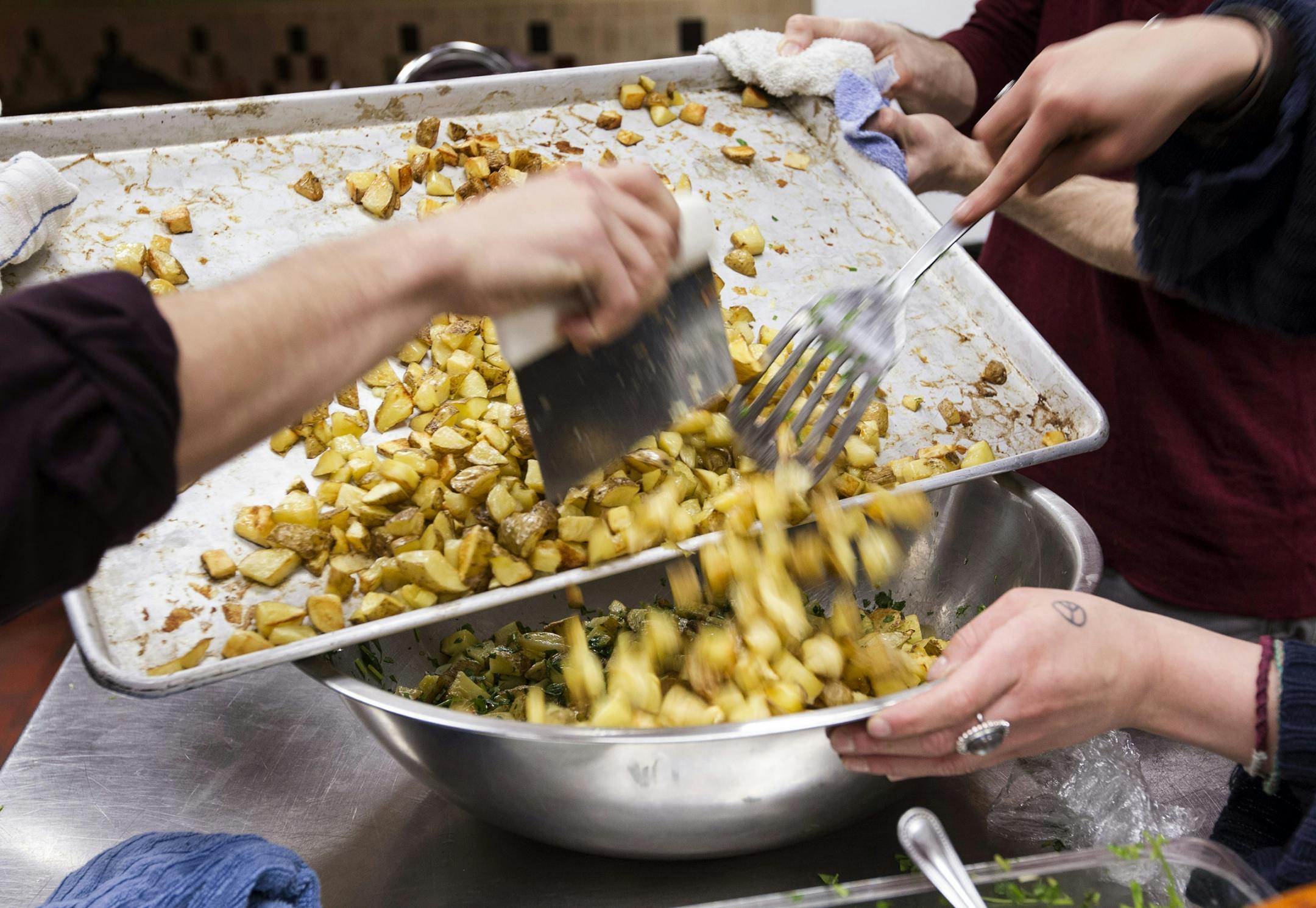Volunteers prepare cilantro roasted potatoes at Eat for Equity's community feast benefitting Urban Ventures at the Urban Ventures headquarters in Minneapolis January 31, 2015.