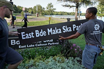 Minneapolis Park and Recreation Board (MPRB) workers install new placards changing East and West Lake Calhoun Parkways to East and West Bde Maka Ska P