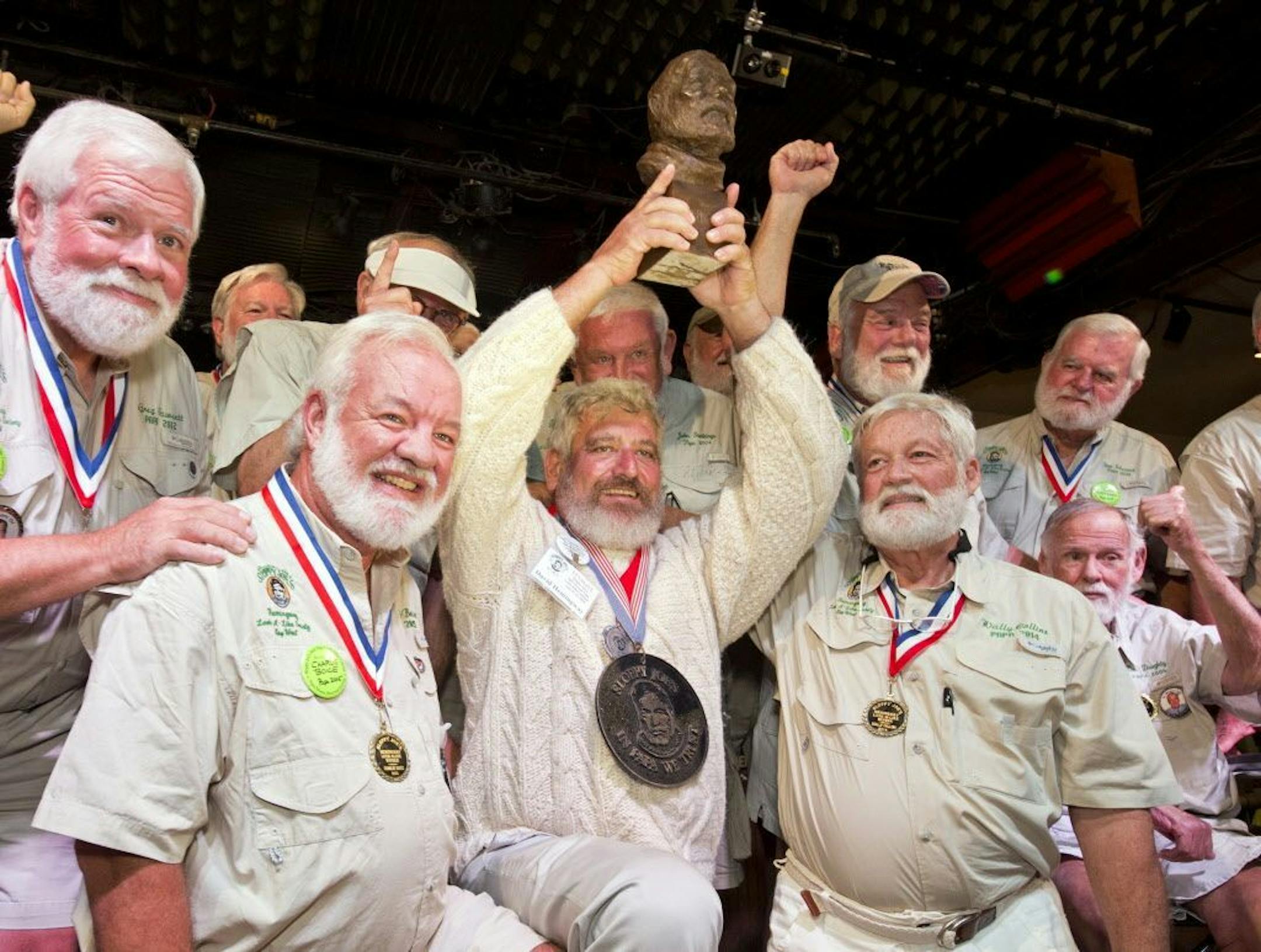 In this Saturday, July 23, 2016, photo provided by the Florida Keys News Bureau, Dave Hemingway, center, hoists his trophy after winning the 2016 Ernest "Papa" Hemingway Look-Alike Contest at Sloppy Joe's Bar in Key West, Fla. Success for Dave Hemingway came on the Macon, N.C., resident's seventh attempt to win the coveted title at the highlight event of the island city's annual Hemingway Days festival that ends Sunday. Dave Hemingway is not related to Ernest Hemingway who lived and wrote in Key