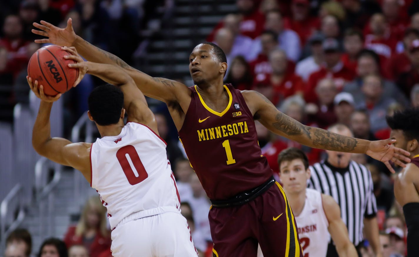 Minnesota's Dupree McBrayer (1) reaches for the ball held by Wisconsin's D'Mitrik Trice (0) during the first half