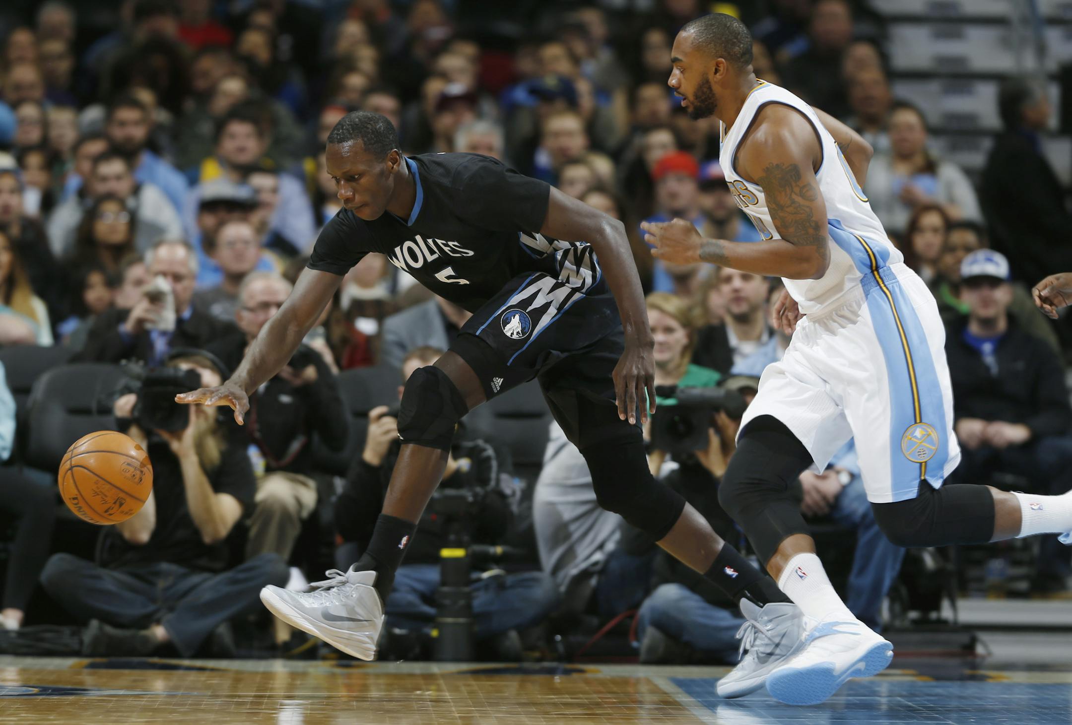 Minnesota Timberwolves center Gorgui Dieng, left, of Senegal, chases down a loose ball as Denver Nuggets forward Darrell Arthur covers in the first quarter of an NBA basketball game Saturday, Jan. 17, 2015, in Denver. (AP Photo/David Zalubowski)