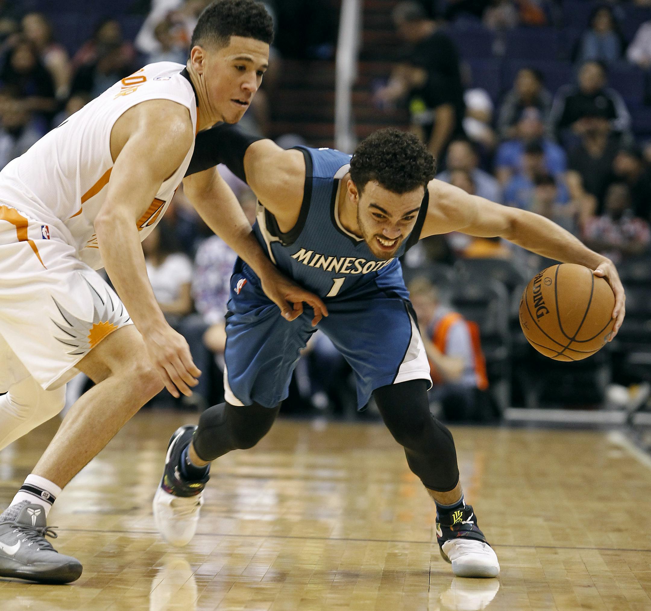 Minnesota Timberwolves guard Tyus Jones (1) advances the ball up court around Phoenix Suns' Devin Booker during the second half of an NBA basketball game, Friday, Nov. 25, 2016, in Phoenix. (AP Photo/Ralph Freso)