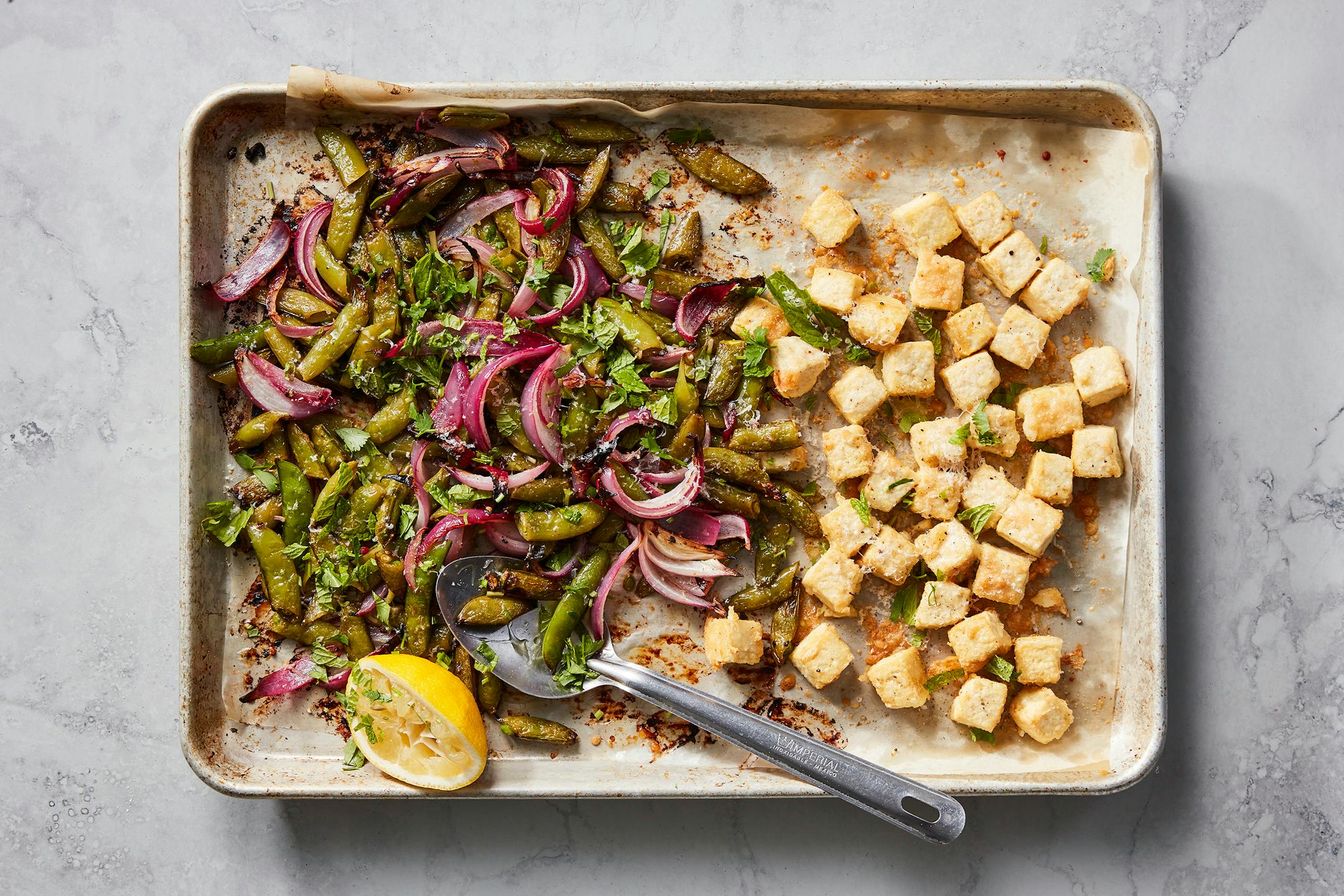 Crispy baked tofu with sugar snap peas in New York, March 28, 2023. A lacy crust of grated Parmesan makes sheet-pan tofu even crispier, Melissa Clark writes. Food styled by Simon Andrews. (Christopher Testani/The New York Times)